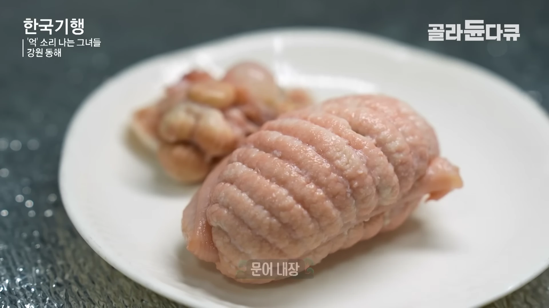 흰 접시 위에 놓인 익힌 문어 내장 요리