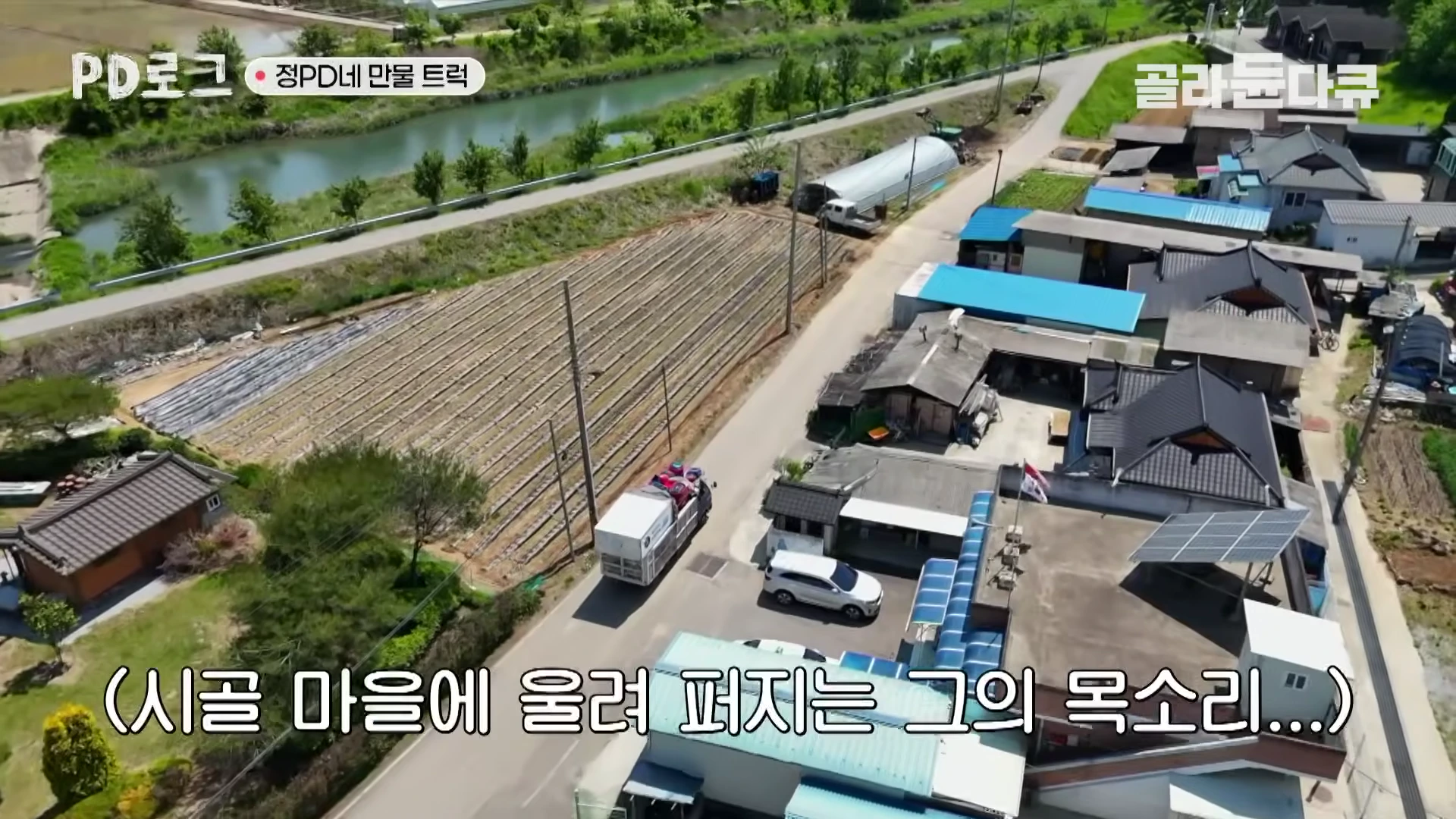 하늘에서 내려다본 시골 마을 길을 따라 만물 트럭이 천천히 이동하고 있는 모습