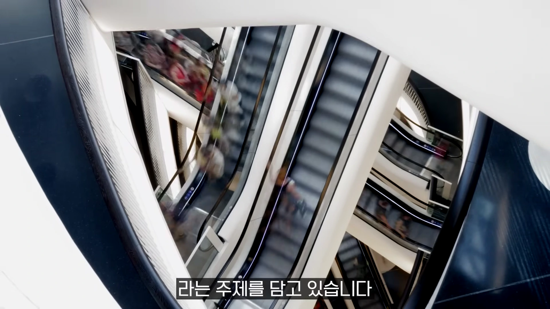 쇼핑몰 내부의 에스컬레이터가 교차하며 사람들이 바쁘게 이동하는 모습