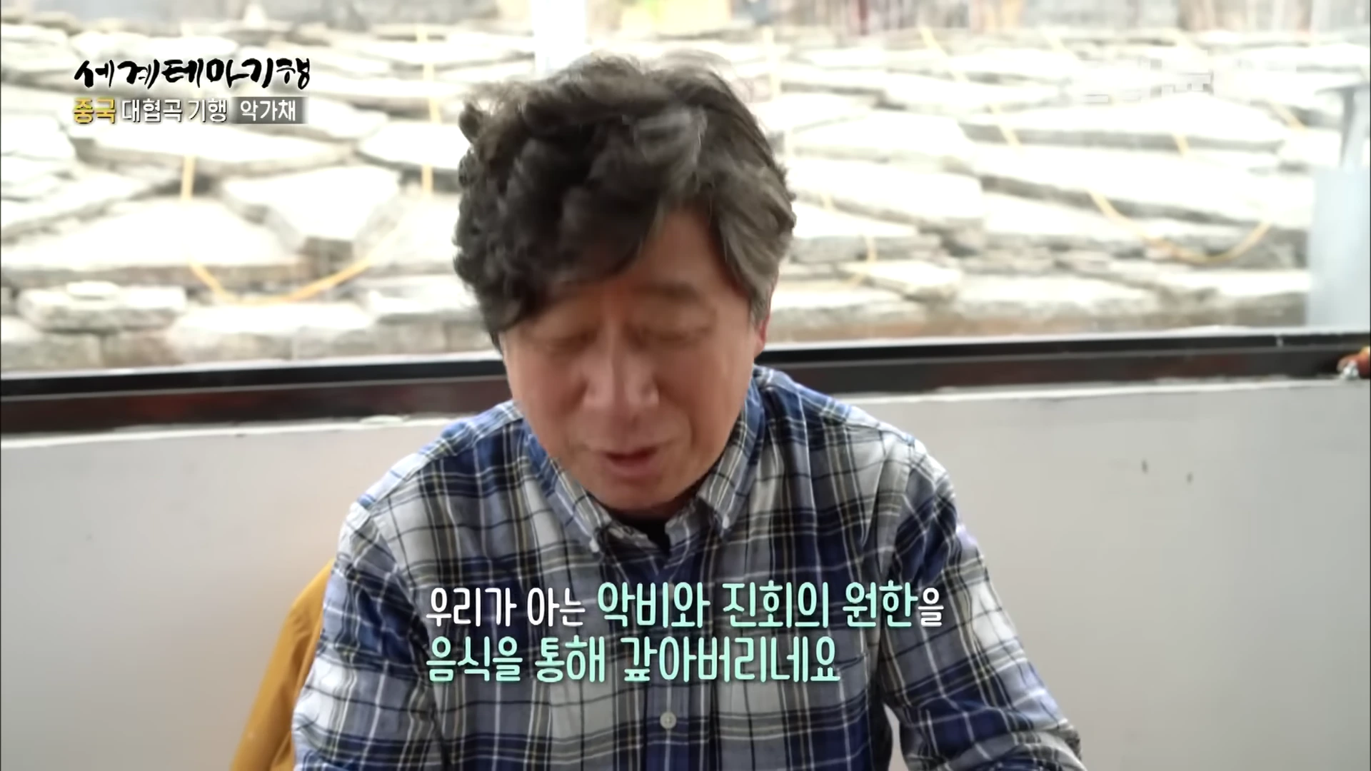 체크무늬 셔츠를 입은 중년 남성이 실내에서 이야기를 나누고 있는 모습