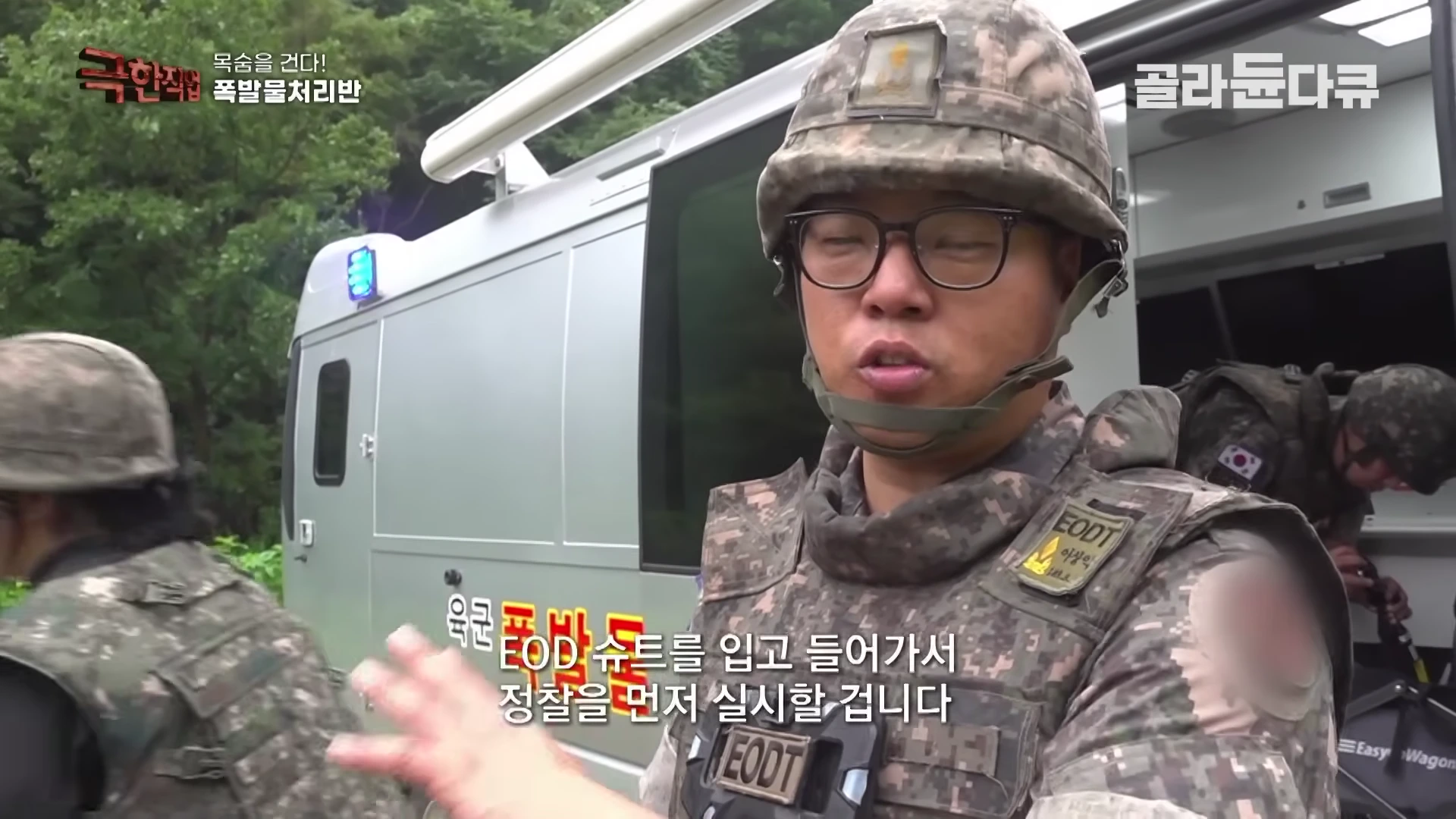 군복과 헬멧을 착용한 폭발물 처리반 대원이 인터뷰하고 있으며 뒤로 작전 차량이 보인다.