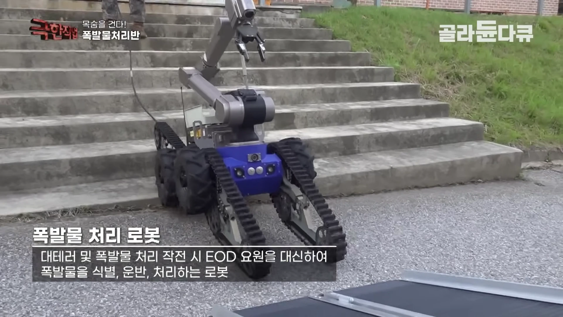 계단 앞에 멈춰 서 있는 파란색 몸체의 무한궤도형 폭발물 처리 로봇