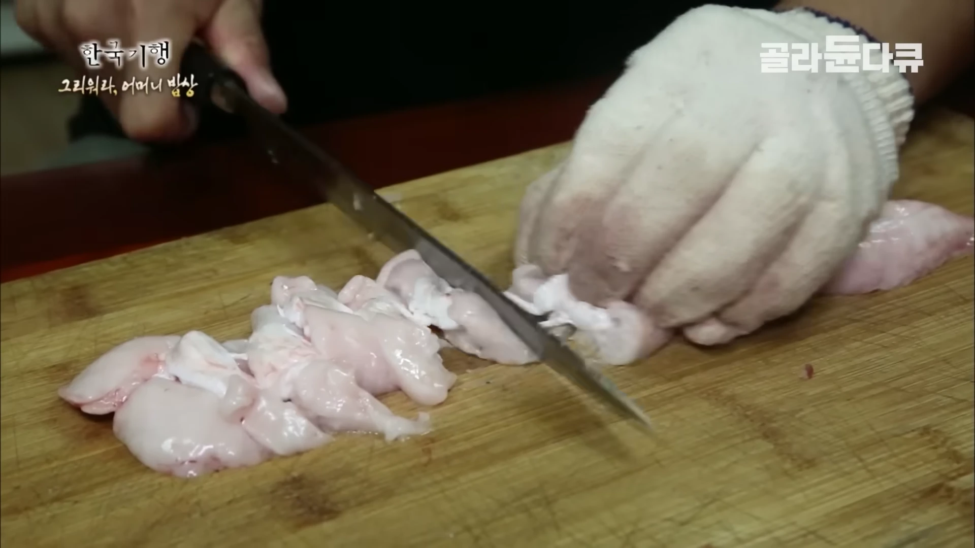 작업용 장갑을 낀 손이 도마 위에서 칼로 민어 부위를 정성스럽게 썰고 있다.