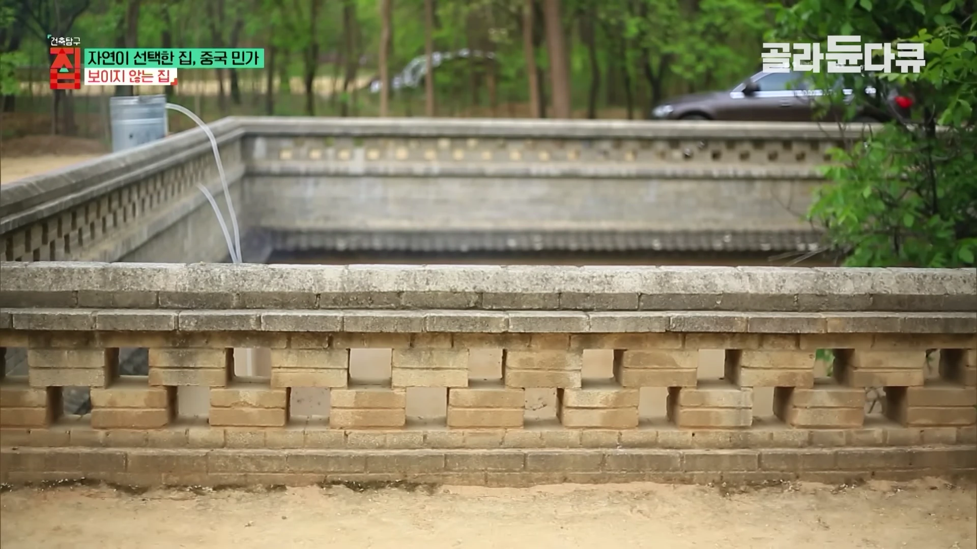 지상에 낮게 설치된 벽돌 담장 너머로 지하로 파인 요동의 마당이 내려다보이는 풍경
