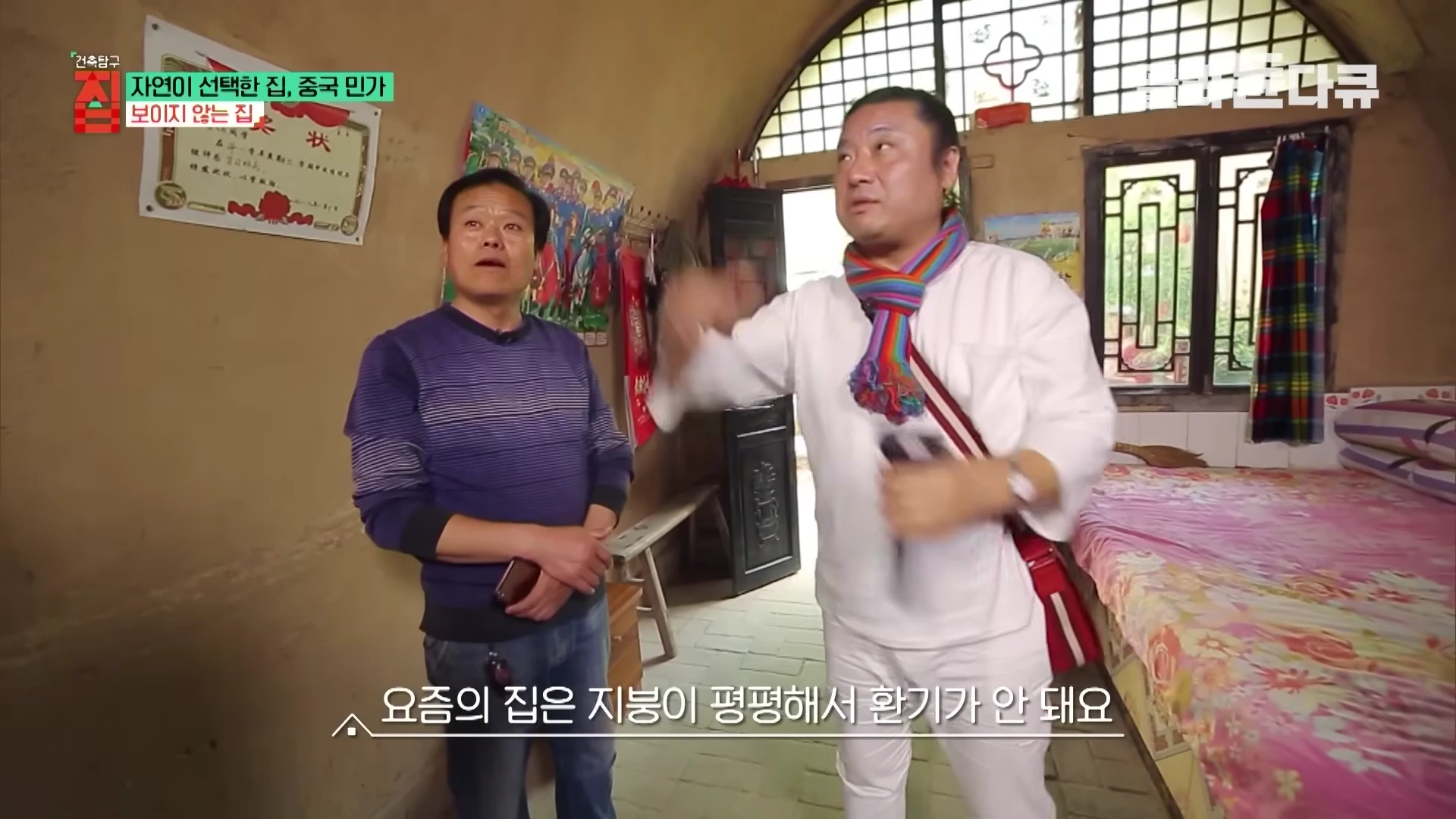 중국 지하 주거지 내부에서 두 남성이 대화를 나누며 손짓으로 환기 구조를 설명하고 있다.