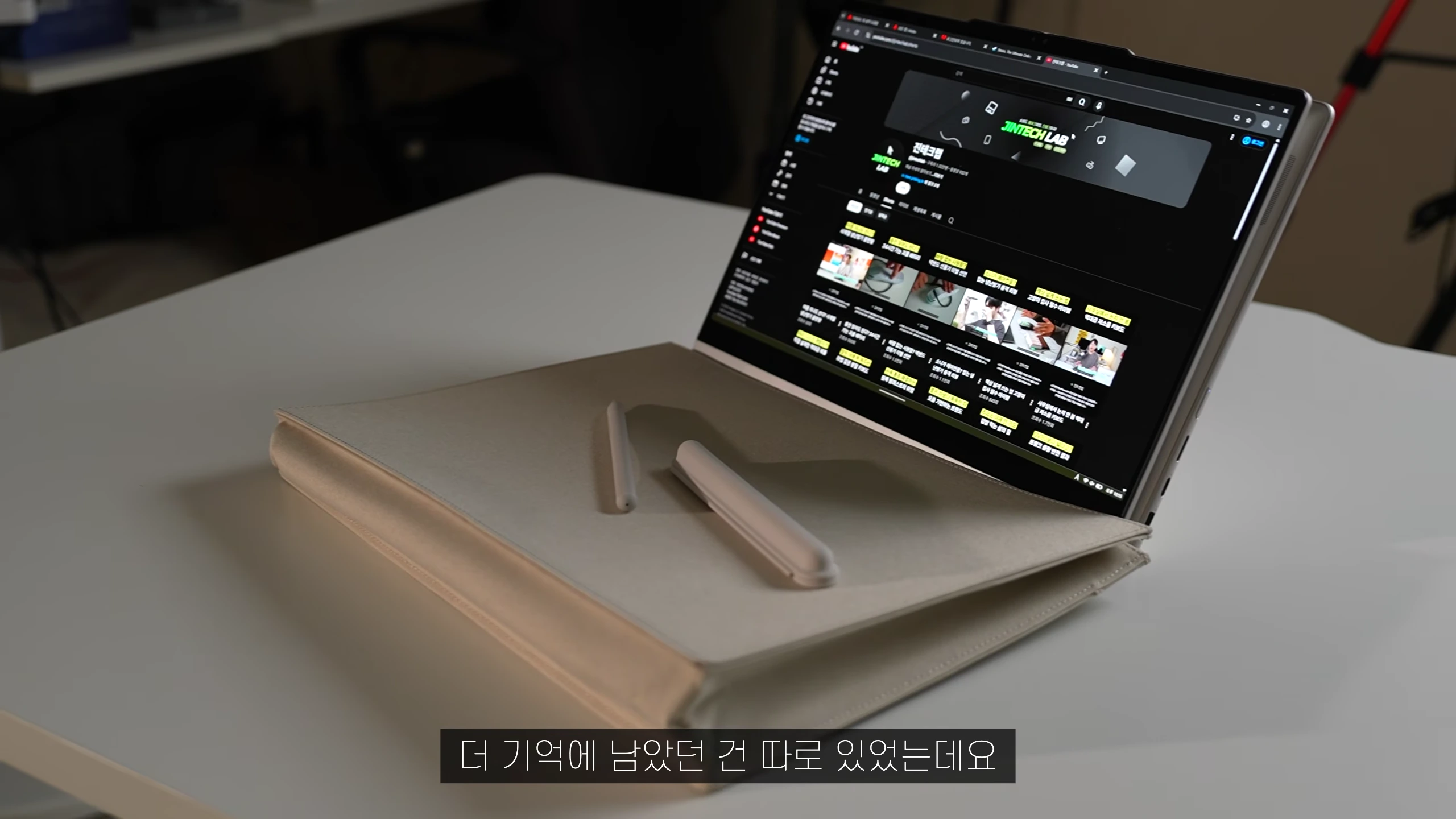 흰색 테이블 위에 놓인 360도 회전형 2-in-1 노트북과 그 위에 올려진 스타일러스 펜