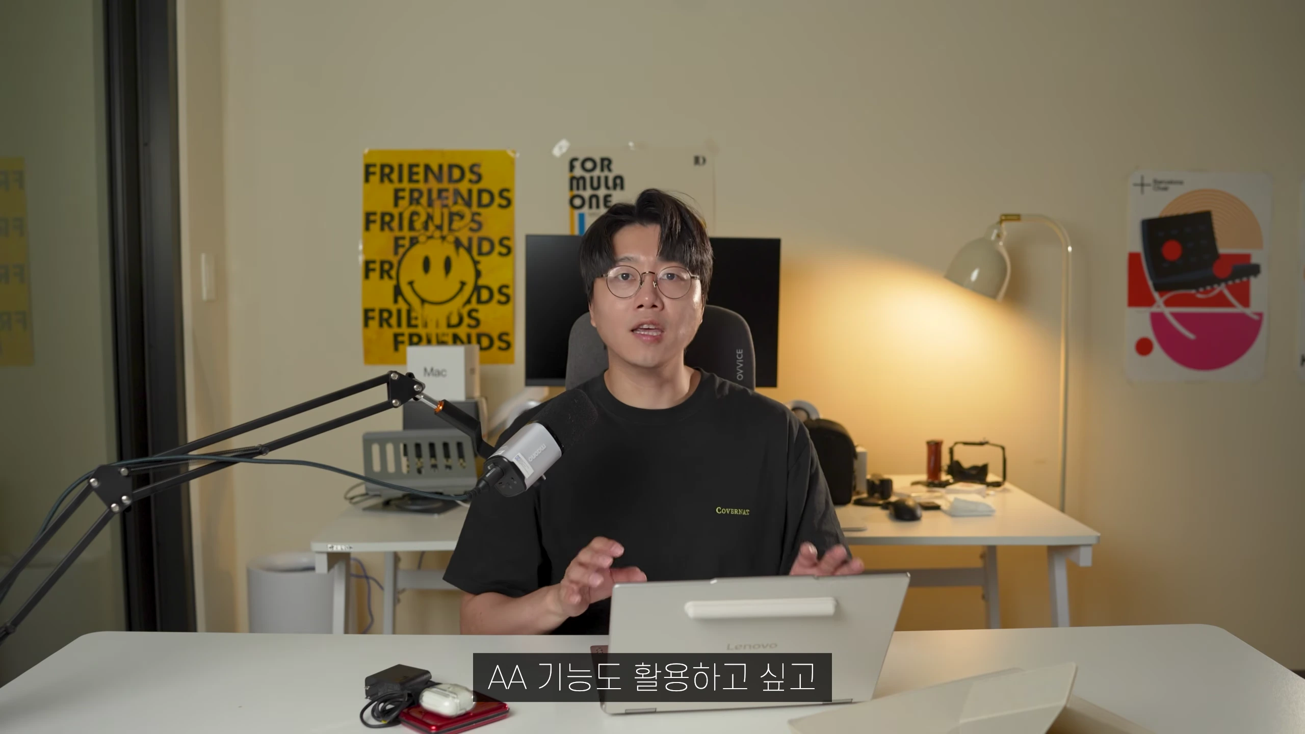 안경을 쓴 남성이 책상 앞에 앉아 노트북을 앞에 두고 이야기를 나누는 모습