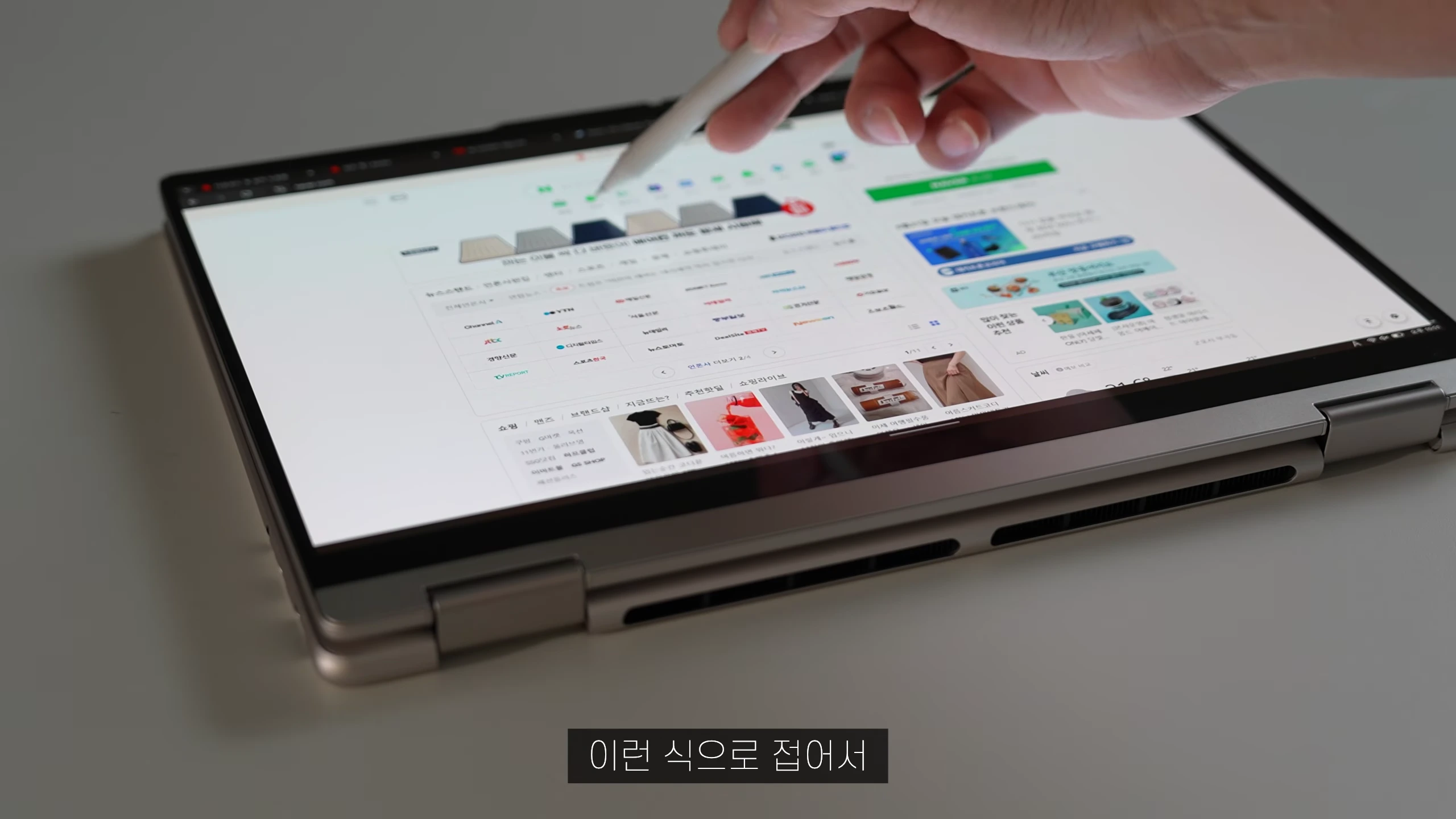 태블릿 형태로 접힌 노트북 화면 위를 스타일러스 펜으로 터치하는 모습