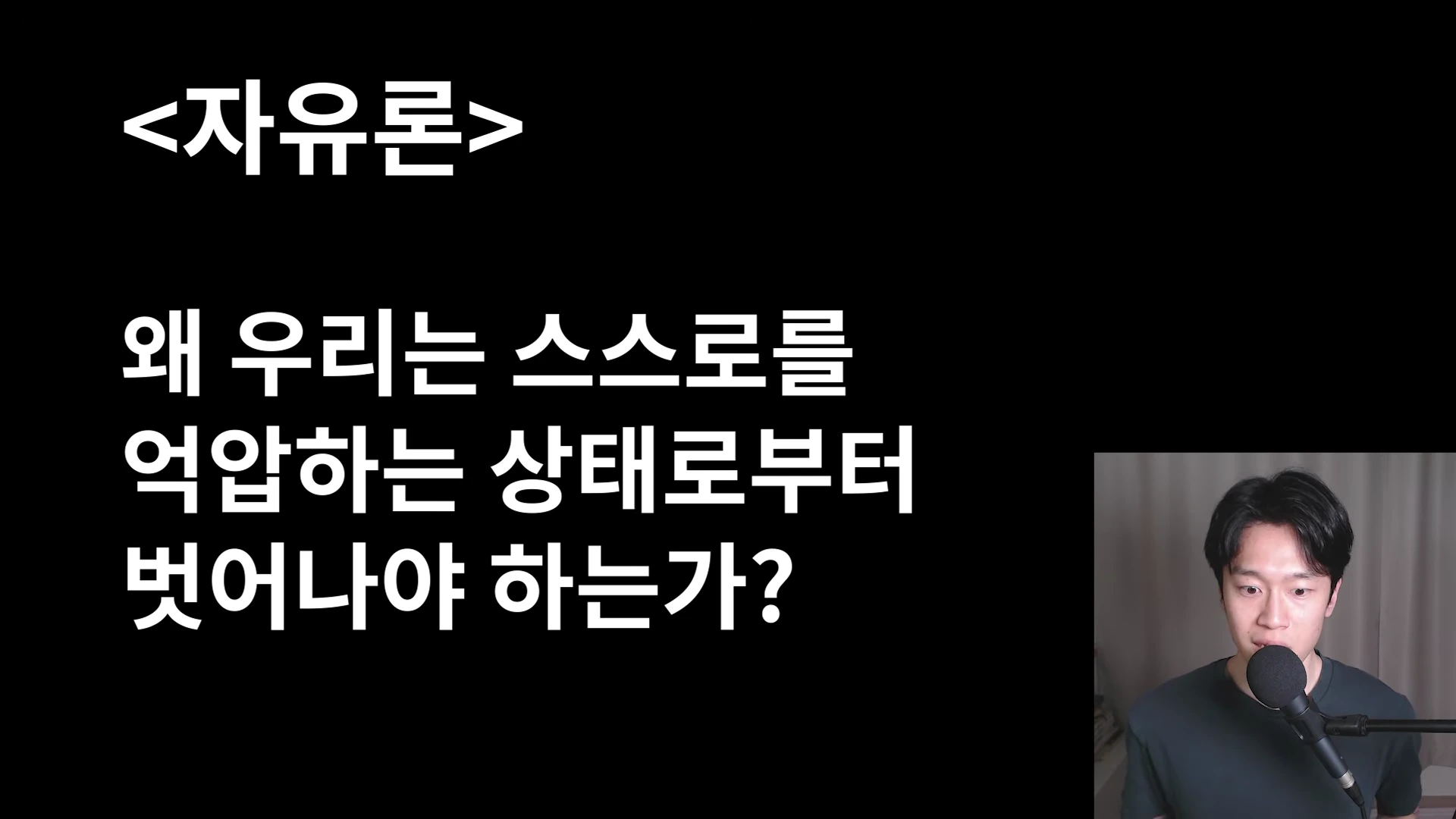 검은 배경에 자유론이라는 제목과 질문이 적힌 화면과 마이크 앞에 앉은 남성