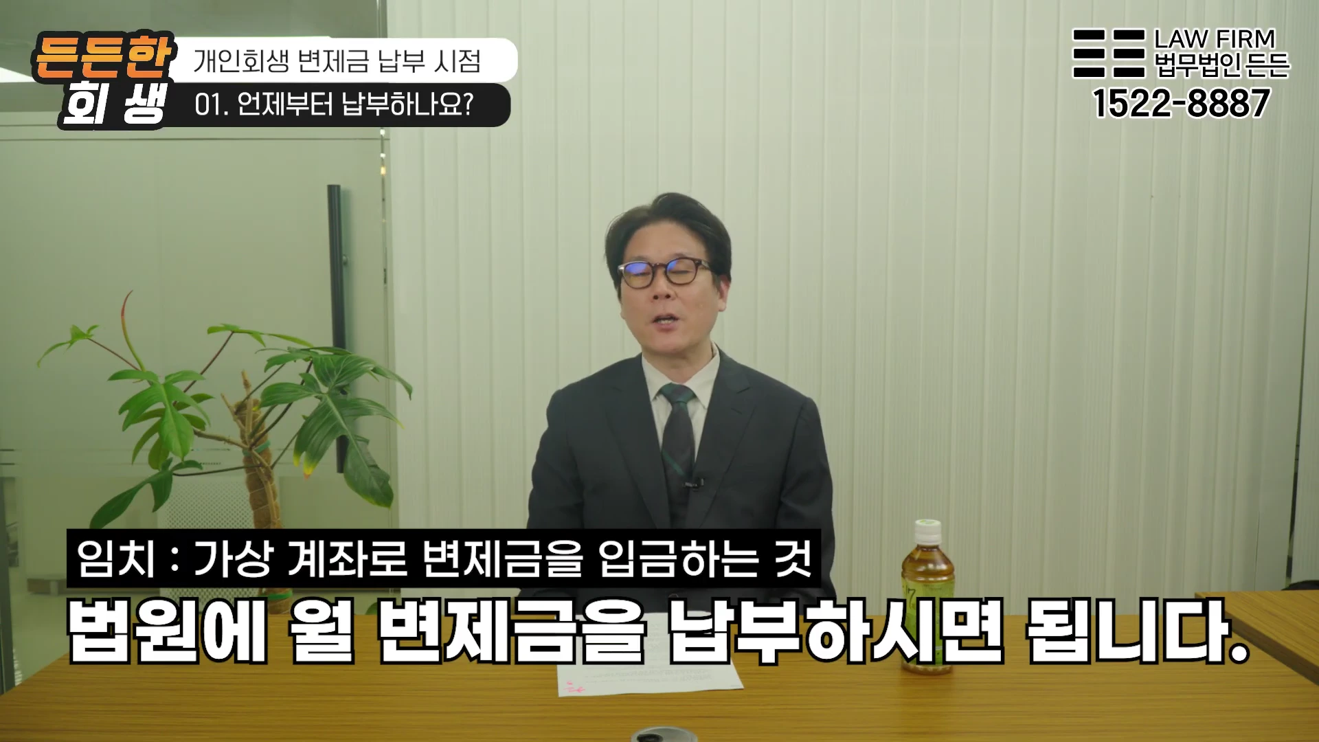 정장을 입은 남성 변호사가 사무실 책상에 앉아 개인회생 변제금 납부에 대해 설명하는 영상 화면