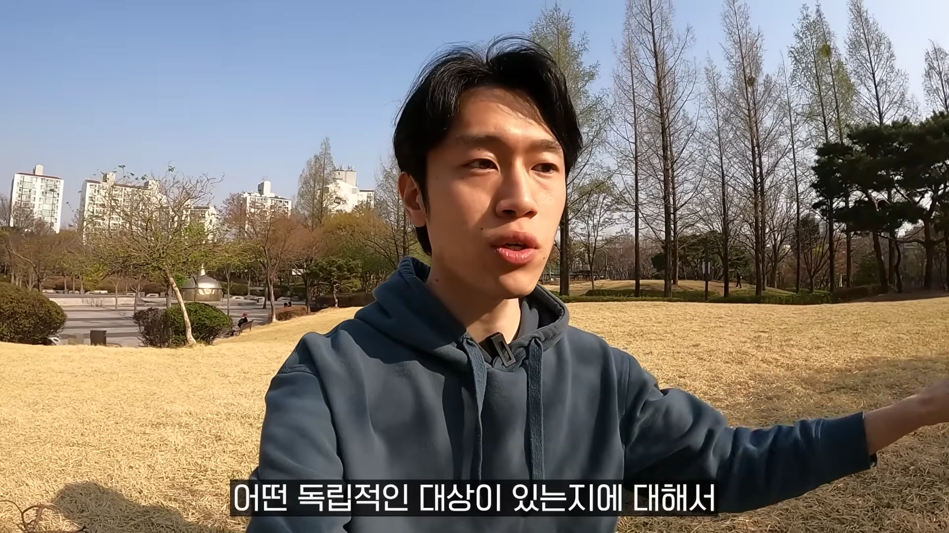 공원 잔디밭에 서서 이야기를 나누는 남성