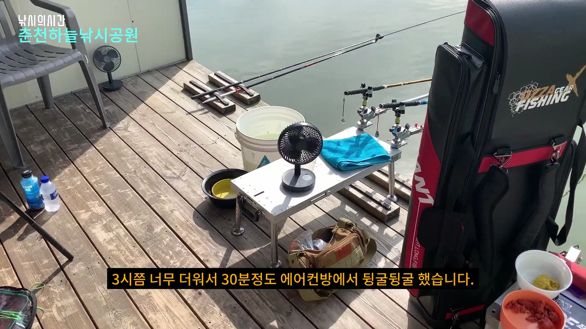 방갈로 앞 나무 데크 위에 낚싯대와 탁상용 선풍기, 낚시 가방 등 장비가 놓여 있는 모습