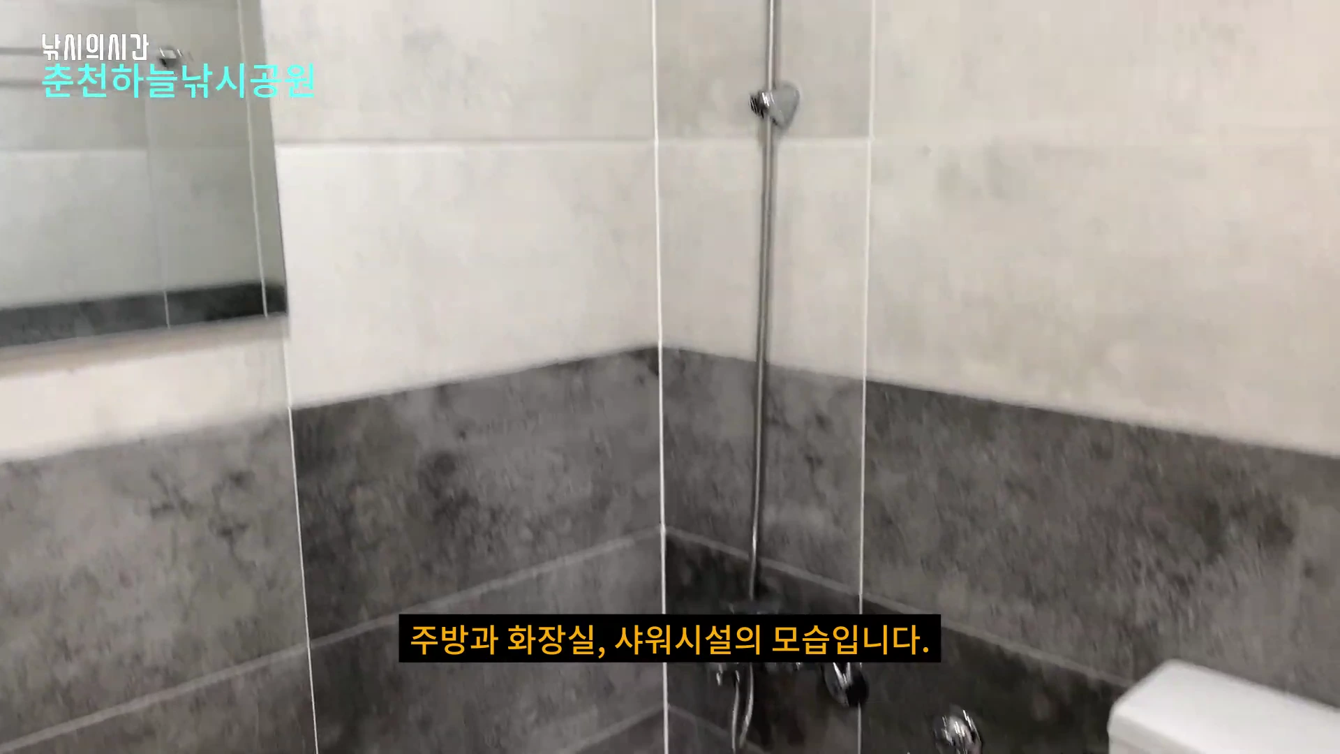 펜션형 방갈로 내부의 깔끔한 타일 벽면과 샤워기, 거울이 설치된 화장실 모습