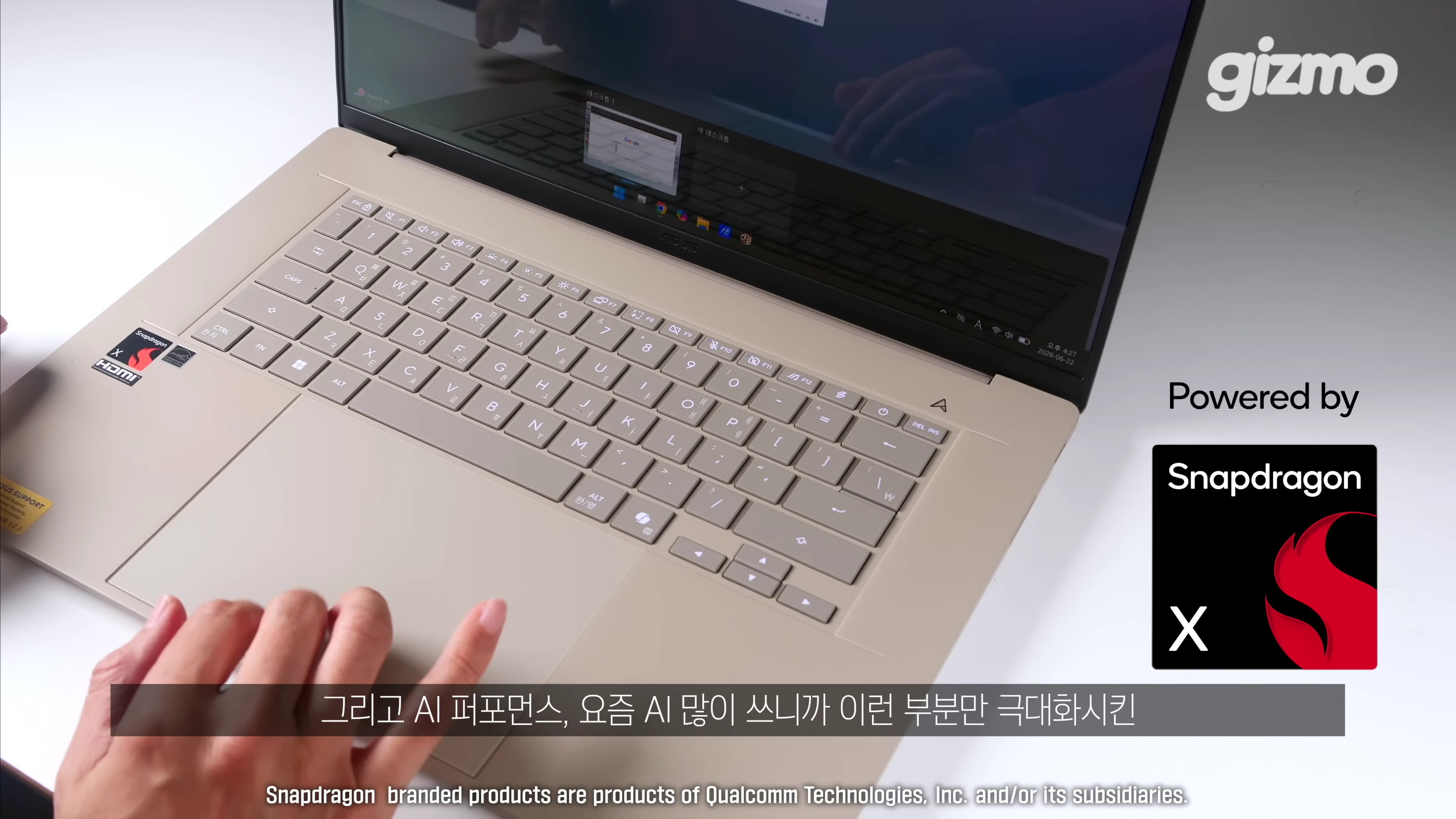 베이지색 젠북 A16 노트북의 키보드와 터치패드를 손으로 조작하는 모습