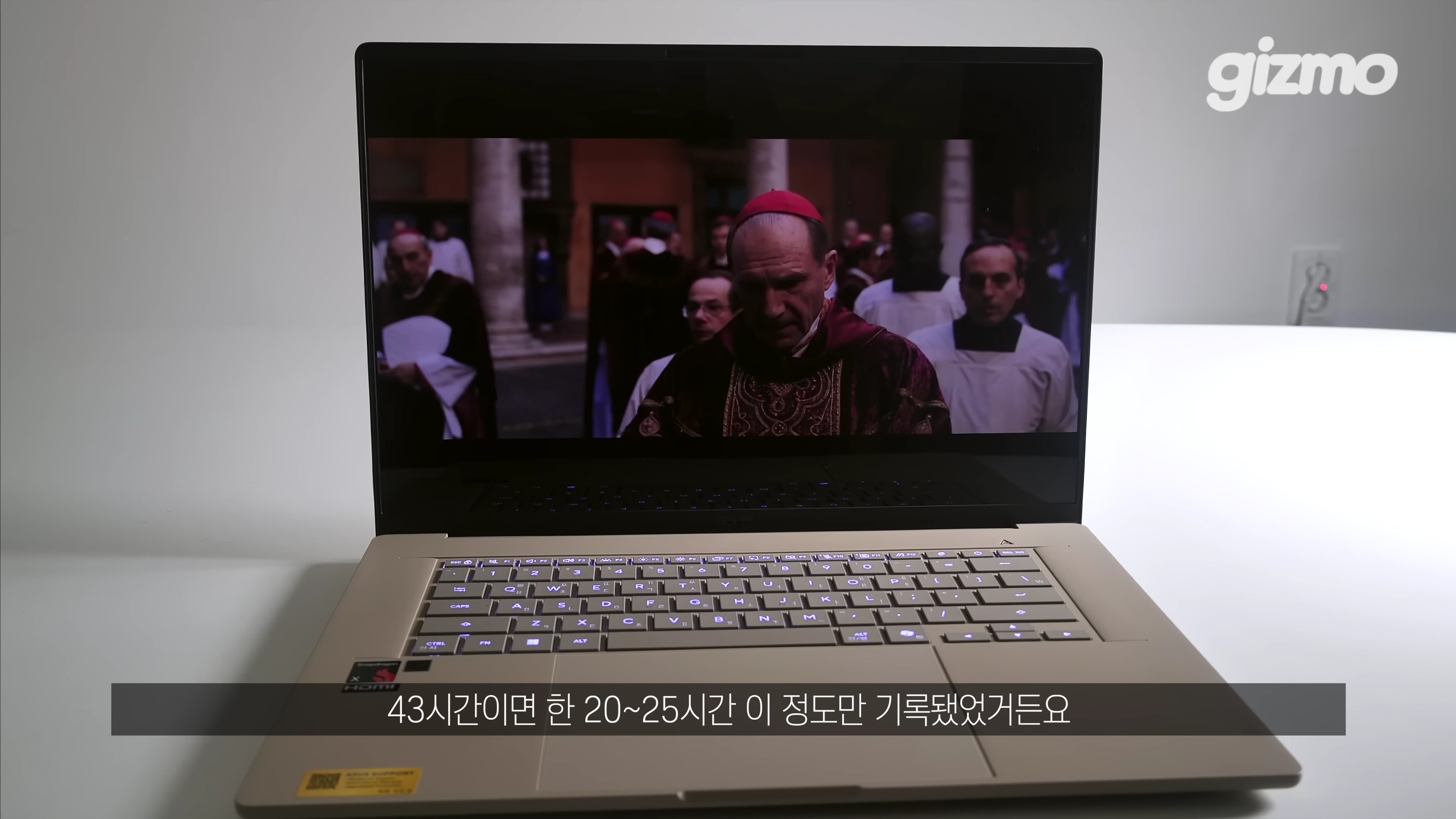 밝은 베이지색 노트북 화면에 영화 장면이 재생되고 있으며, 하단에는 한국어 자막이 표시되어 있습니다.