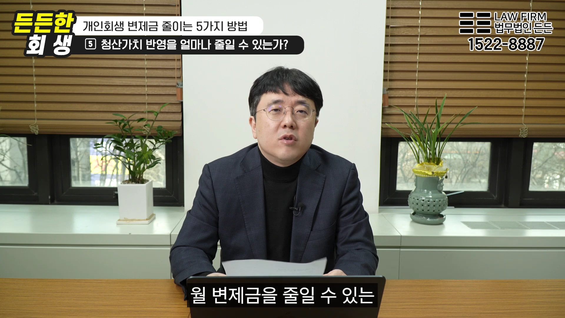안경을 쓴 남성이 사무실 책상에 앉아 서류를 보며 설명하는 모습이 담긴 영상 화면