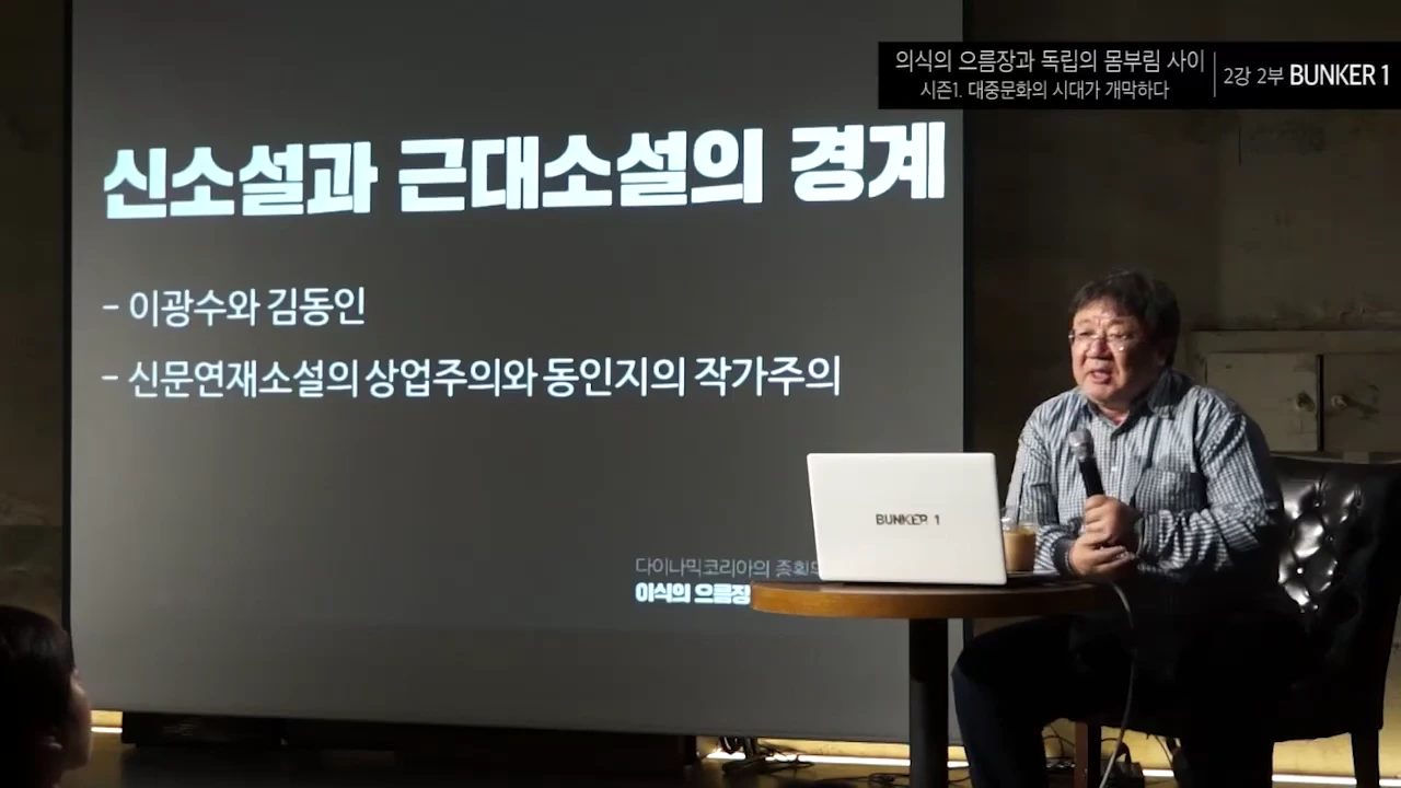 강연자가 마이크를 들고 앉아 있고, 뒤편 스크린에는 '신소설과 근대소설의 경계'라는 제목의 발표 자료가 떠 있습니다.