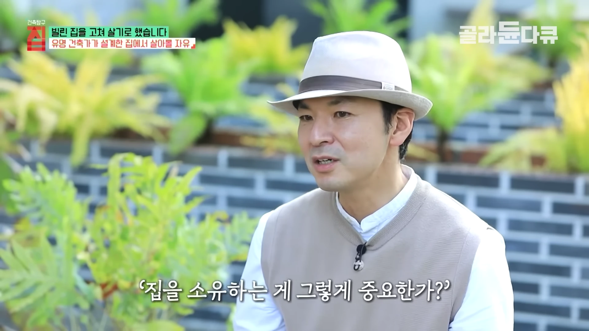 중절모를 쓴 남성이 정원을 배경으로 인터뷰하고 있으며, 화면 하단에는 '집을 소유하는 게 그렇게 중요한가?'라는 자막이 떠 있다.