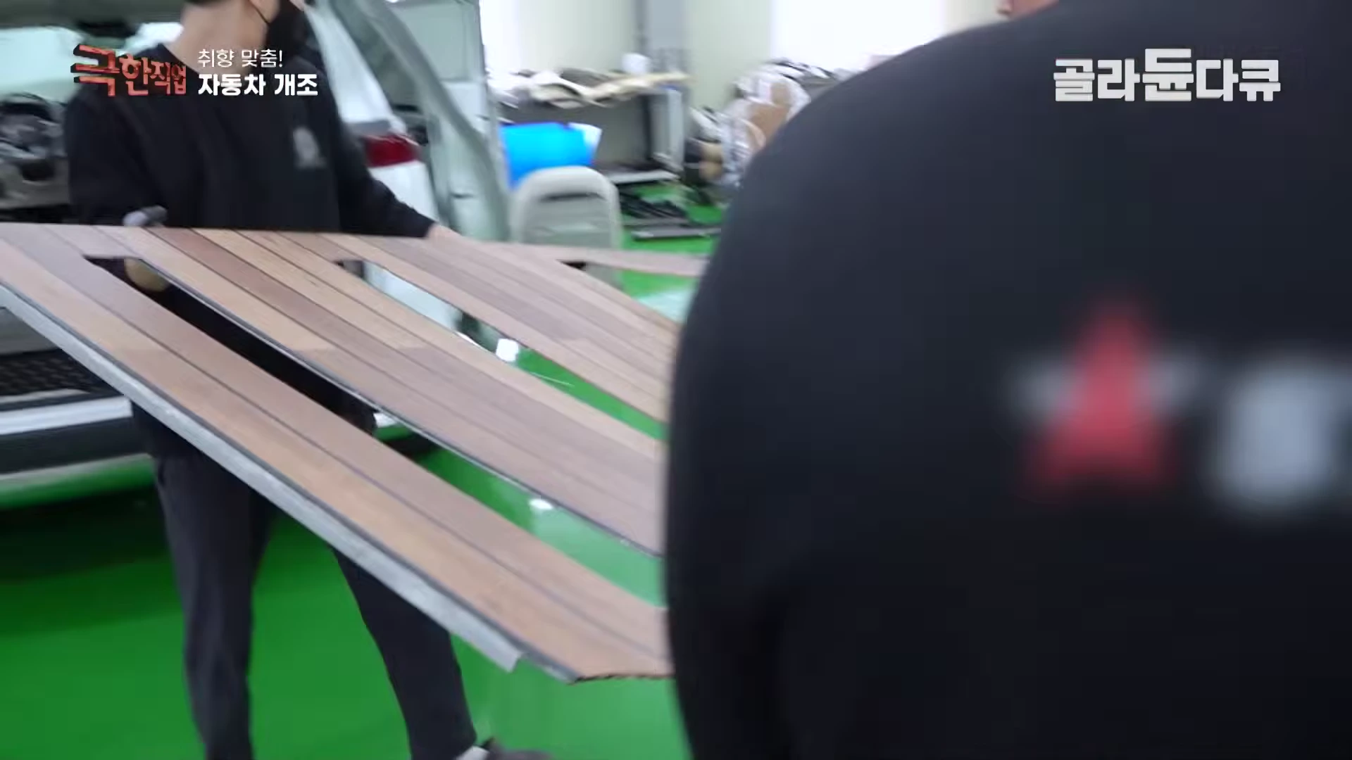 작업자들이 자동차 바닥에 깔 나무 무늬 마감재를 조심스럽게 옮기고 있다.