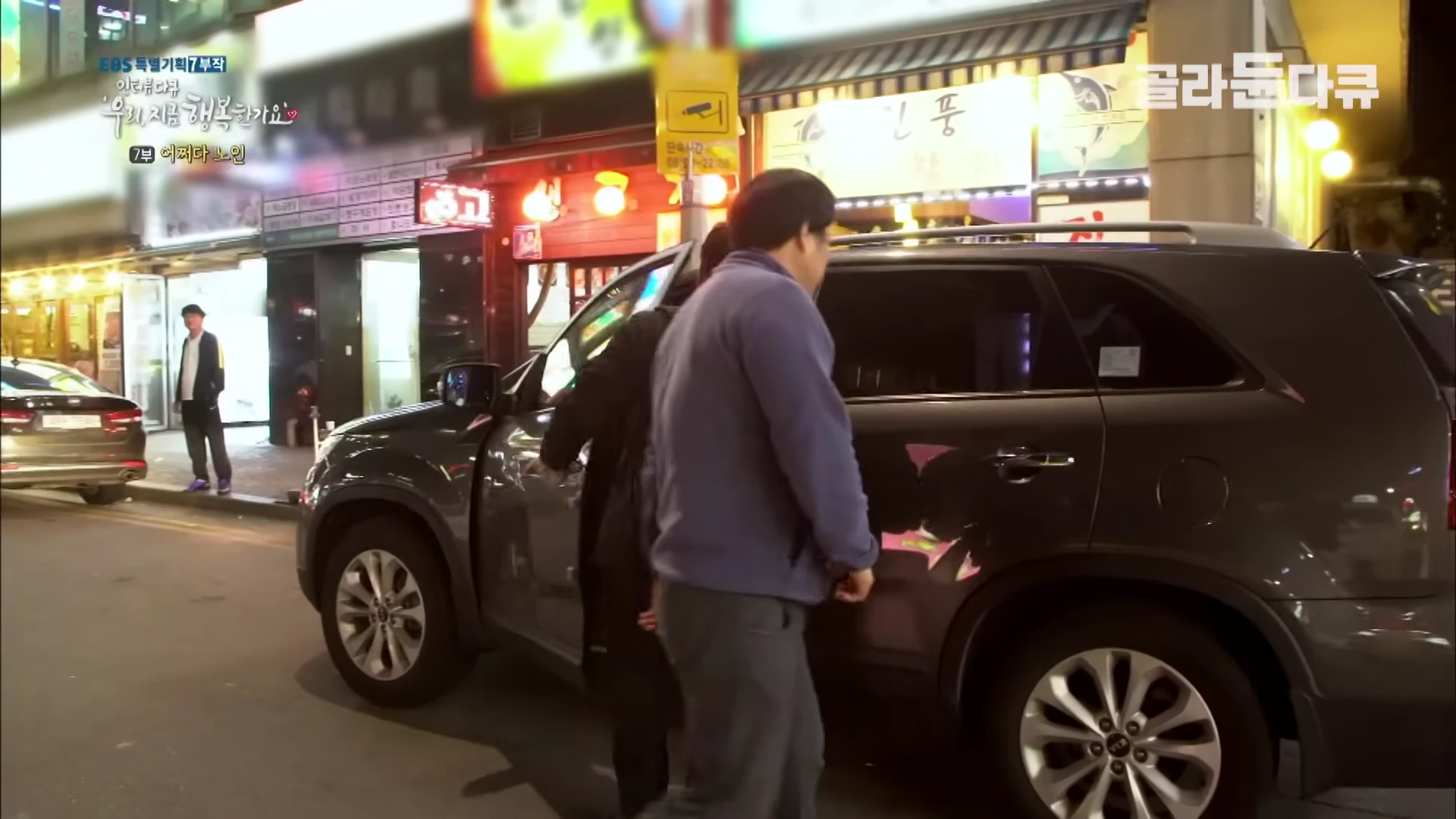 밤거리에서 한 남성이 검은색 SUV 차량의 운전석 문을 열고 탑승하려는 모습