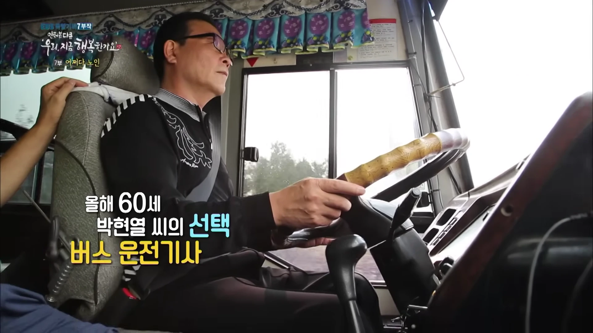 버스 운전석에 앉아 핸들을 잡고 운전 연습을 하는 중년 남성의 모습