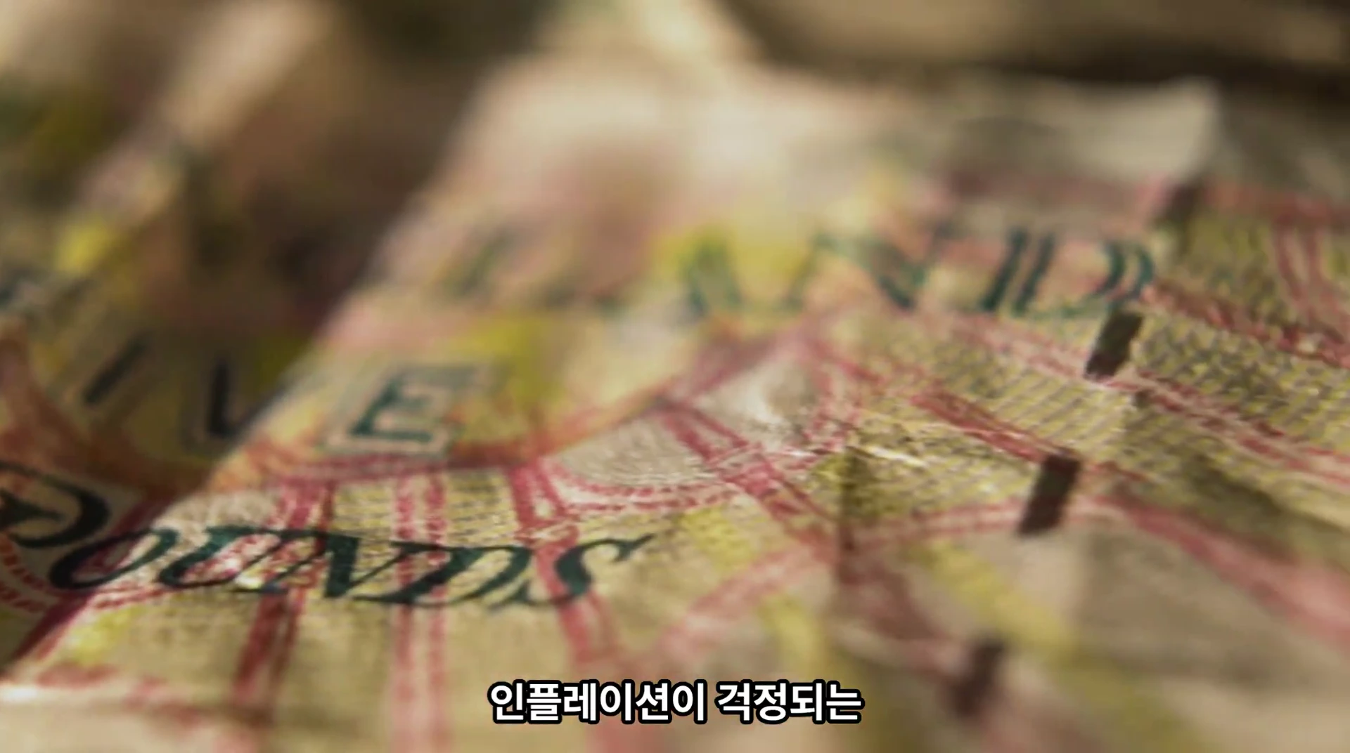 구겨진 지폐의 일부분이 클로즈업되어 있으며, 화면 하단에는 자막이 표시되어 있습니다.