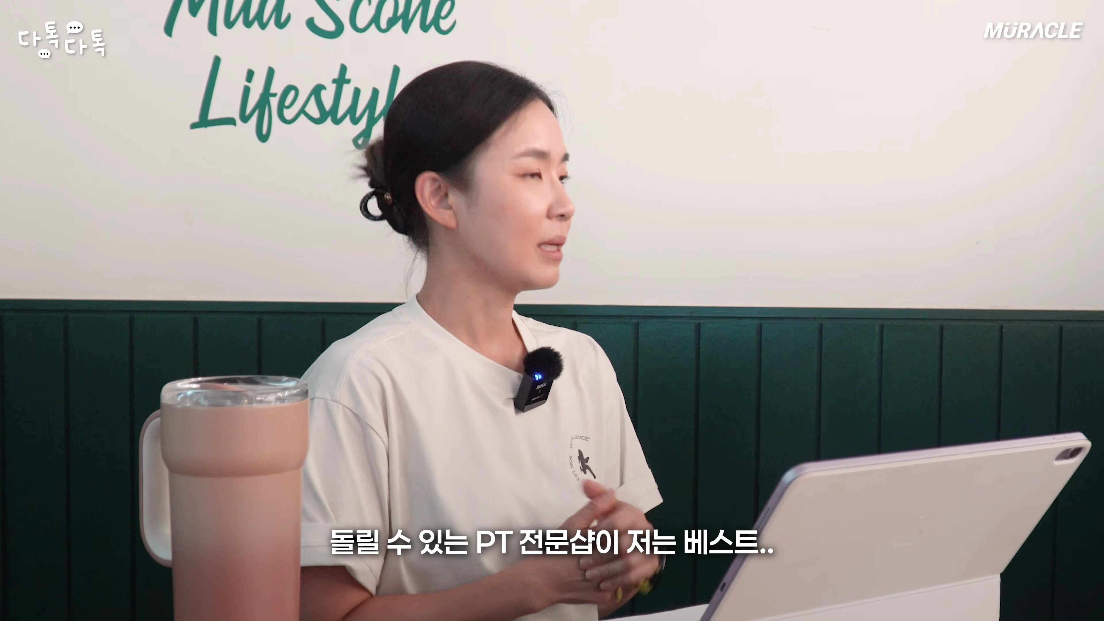 흰색 티셔츠를 입은 여성이 테이블 앞에 앉아 이야기를 나누고 있는 모습