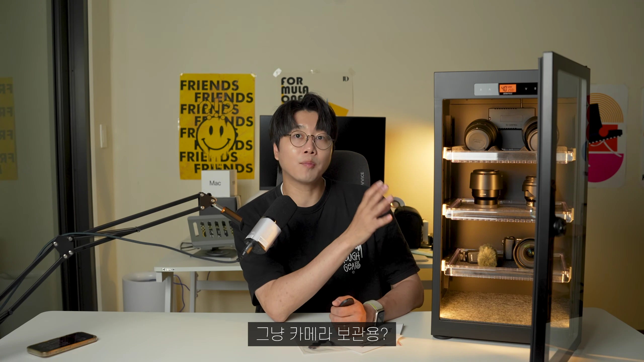 작업실 책상에 앉아 카메라 제습함을 소개하는 남성