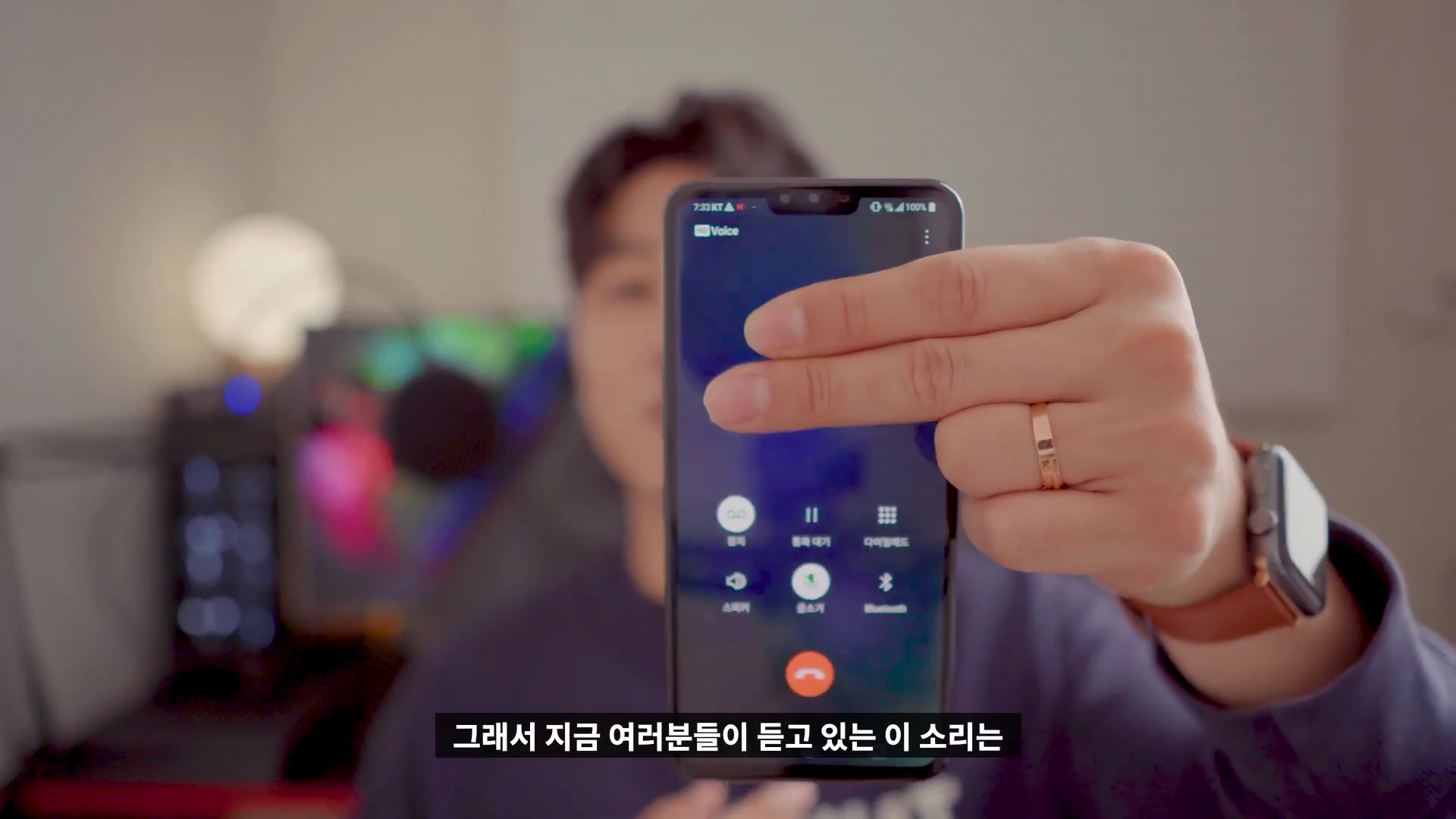 한 남성이 스마트폰 통화 화면을 카메라 쪽으로 들어 보이고 있다.