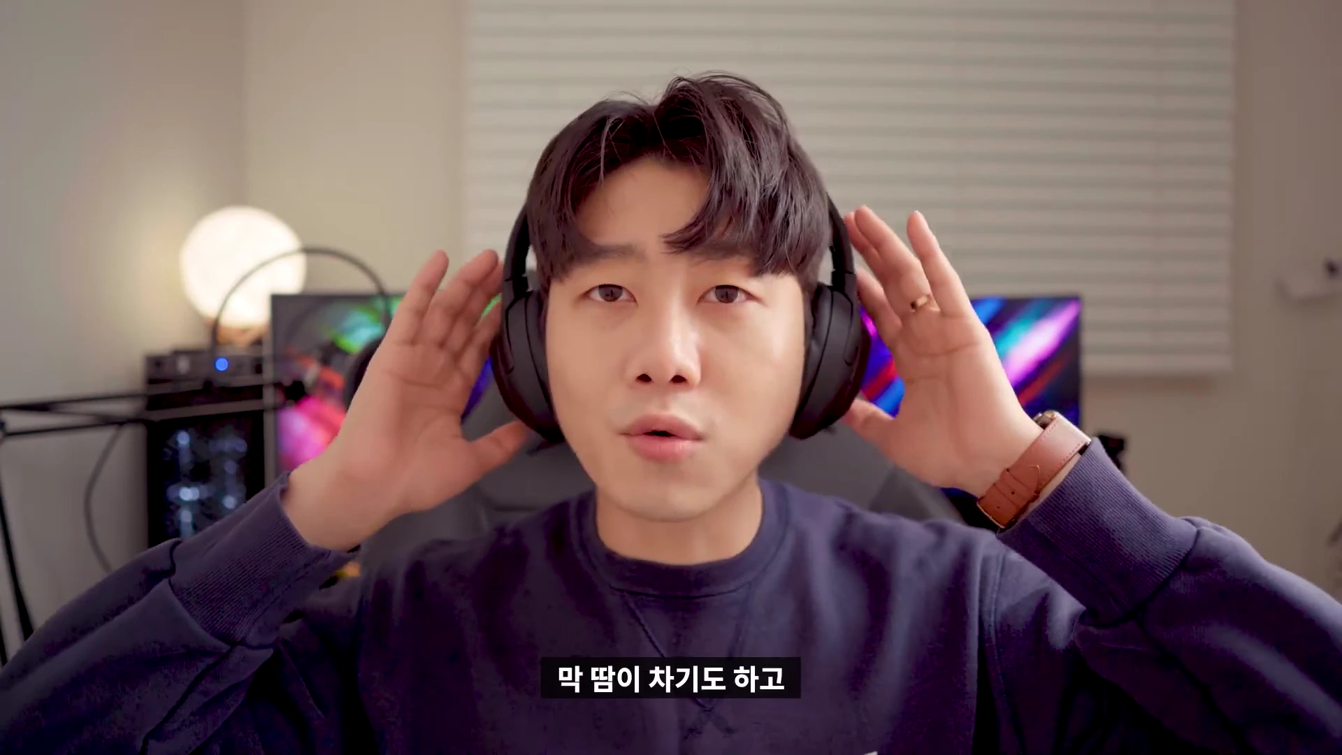 실내에서 검은색 헤드폰을 착용하고 정면을 바라보는 남성