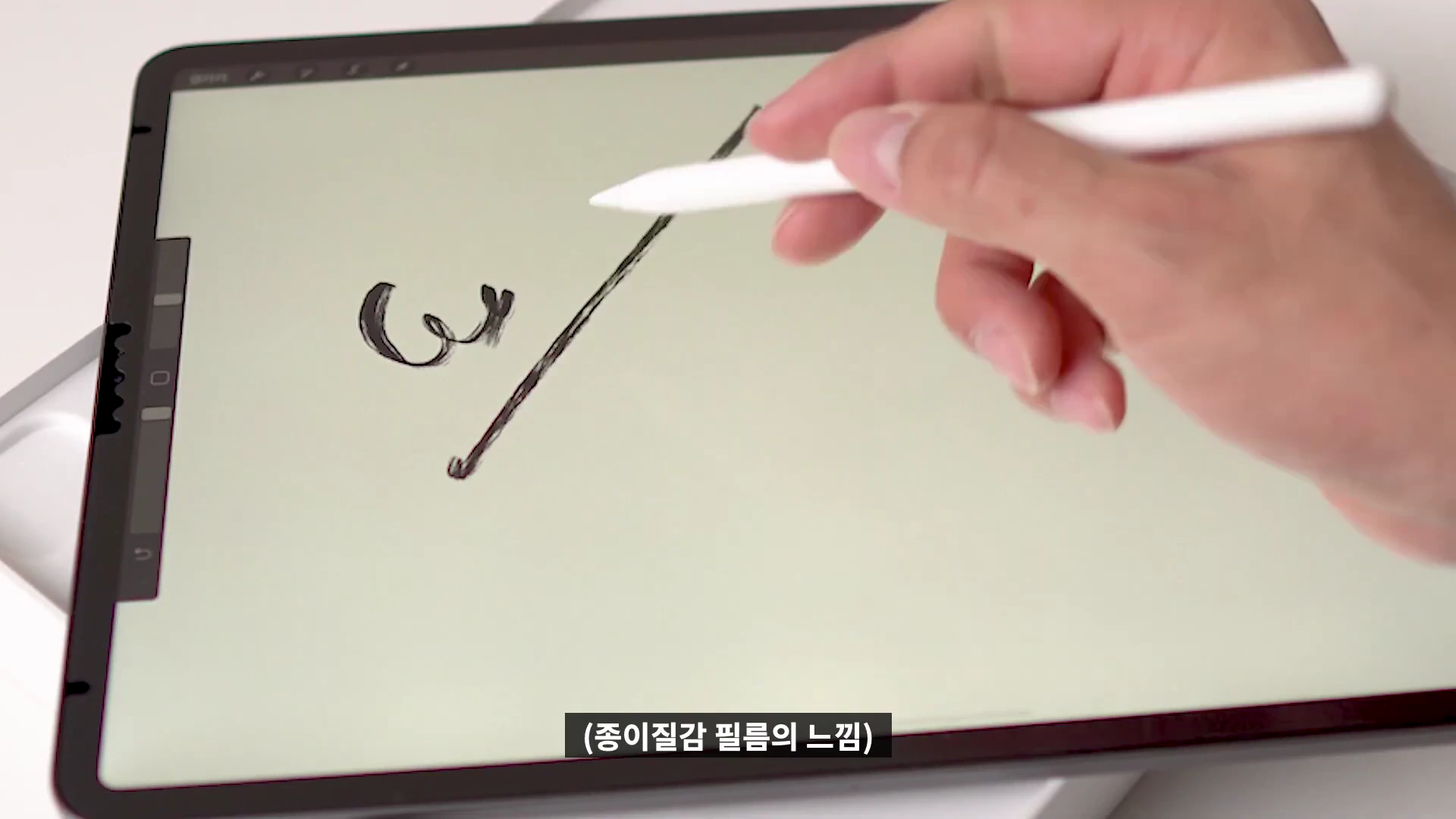 태블릿 화면 위에서 애플펜슬로 선과 글자를 그리는 손의 모습