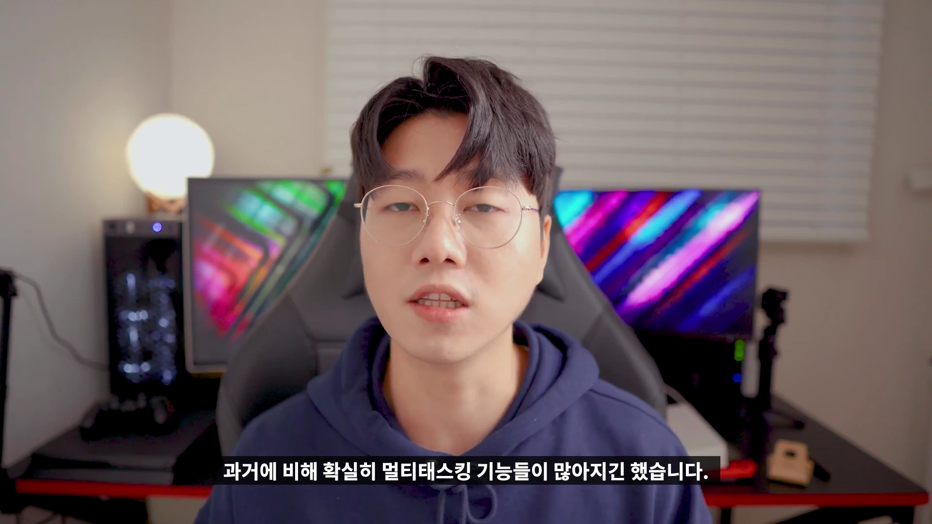 안경을 쓴 남성이 어두운 조명의 방 안에서 카메라를 응시하며 이야기하고 있고, 하단에는 자막이 표시되어 있습니다.