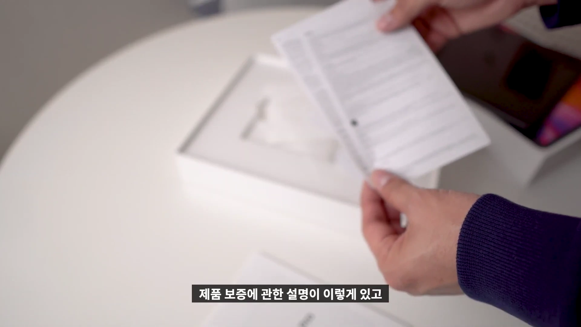 아이패드 프로 박스 안의 사용 설명서를 손으로 펼쳐 보여주는 모습