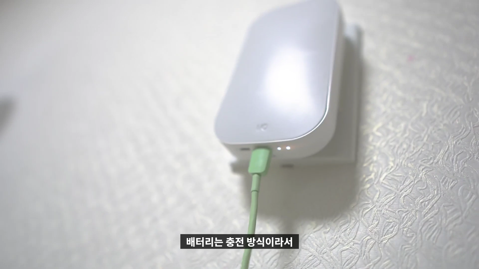 벽면에 부착된 스마트 스위치에 충전 케이블이 연결되어 있는 모습
