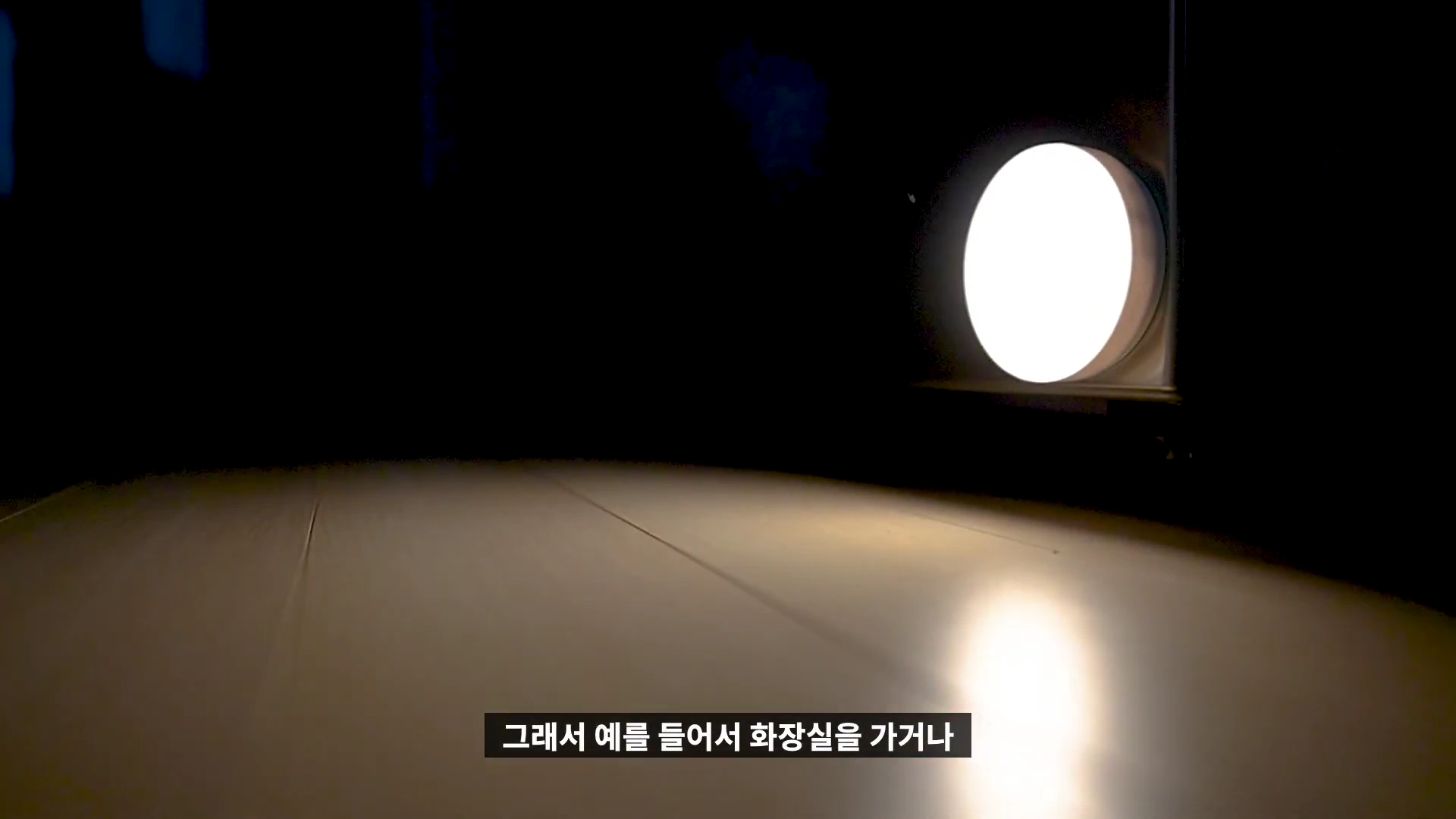 어두운 공간에서 원형 센서등이 은은하게 빛을 내며 바닥을 비추고 있는 모습