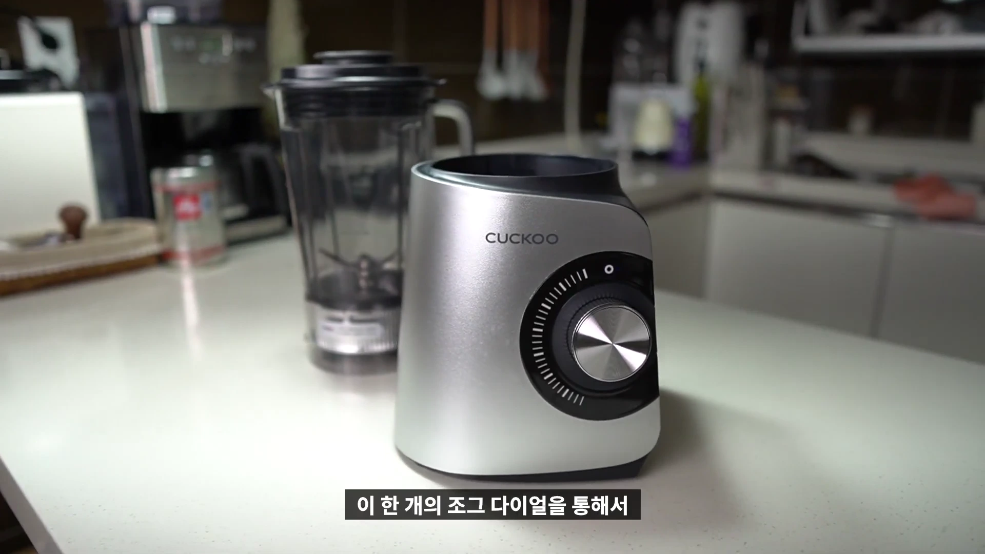 주방 조리대 위에 놓인 은색 블렌더 본체와 투명한 용기