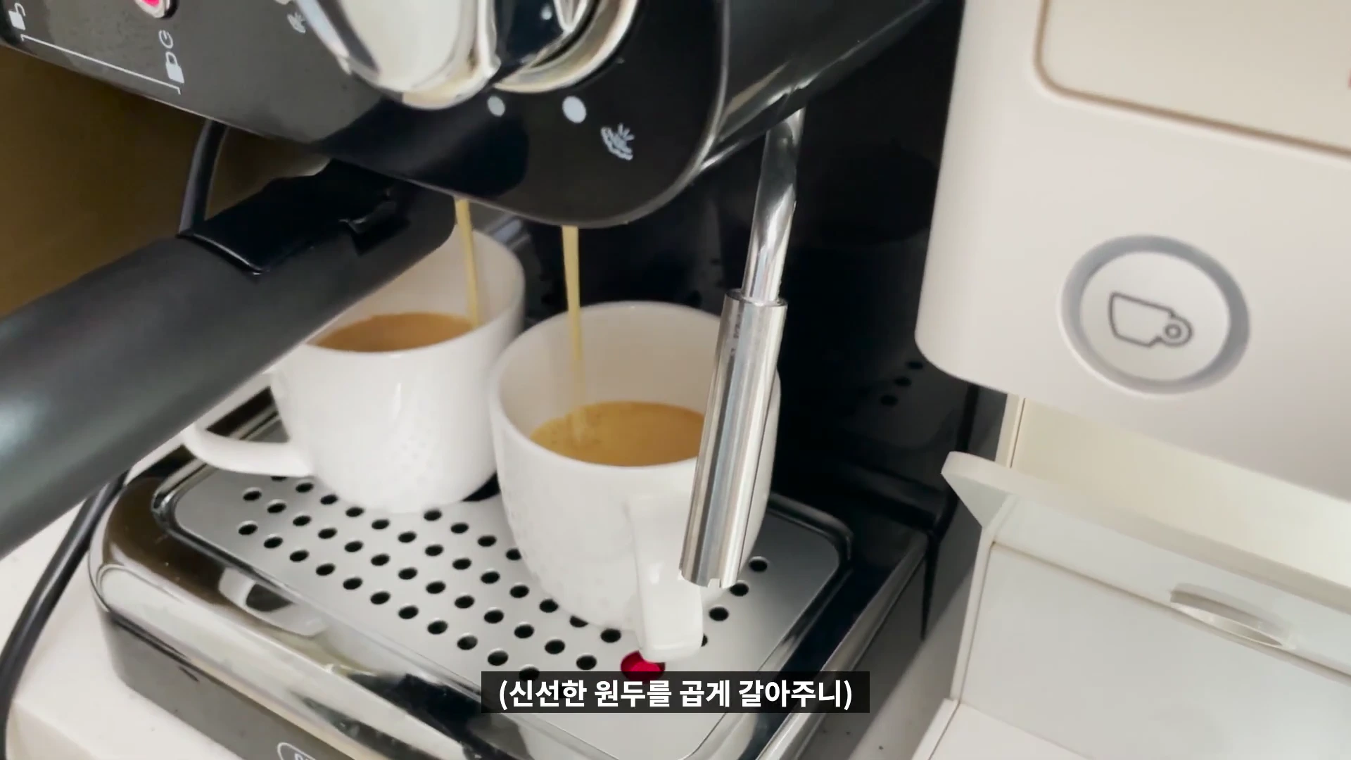 커피 머신에서 두 개의 흰색 컵으로 에스프레소가 추출되는 모습