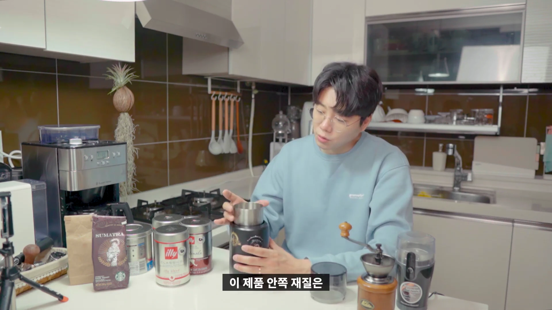주방에서 남성이 전동 그라인더의 내부를 보여주며 설명하고 있는 모습