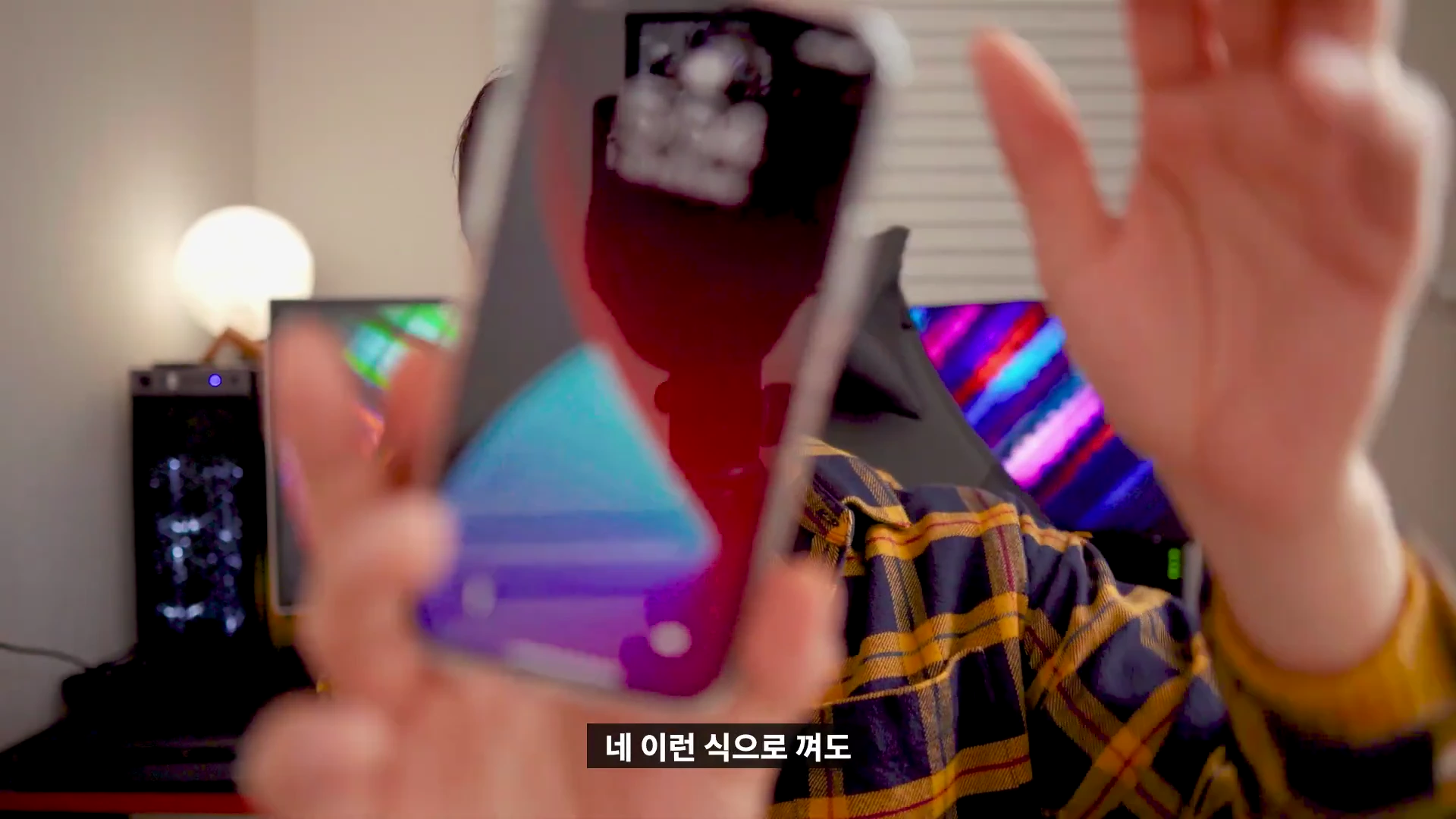 체크무늬 셔츠를 입은 사람이 아이폰을 들어 화면의 맥세이프 애니메이션을 보여주고 있다.