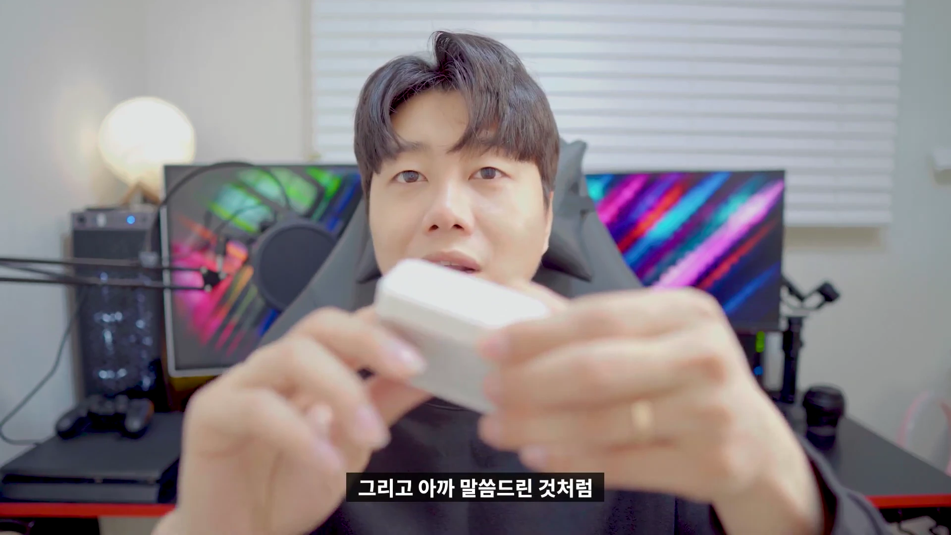 스튜디오에서 한 남성이 무선 이어폰 충전 케이스를 손에 들고 설명하는 모습