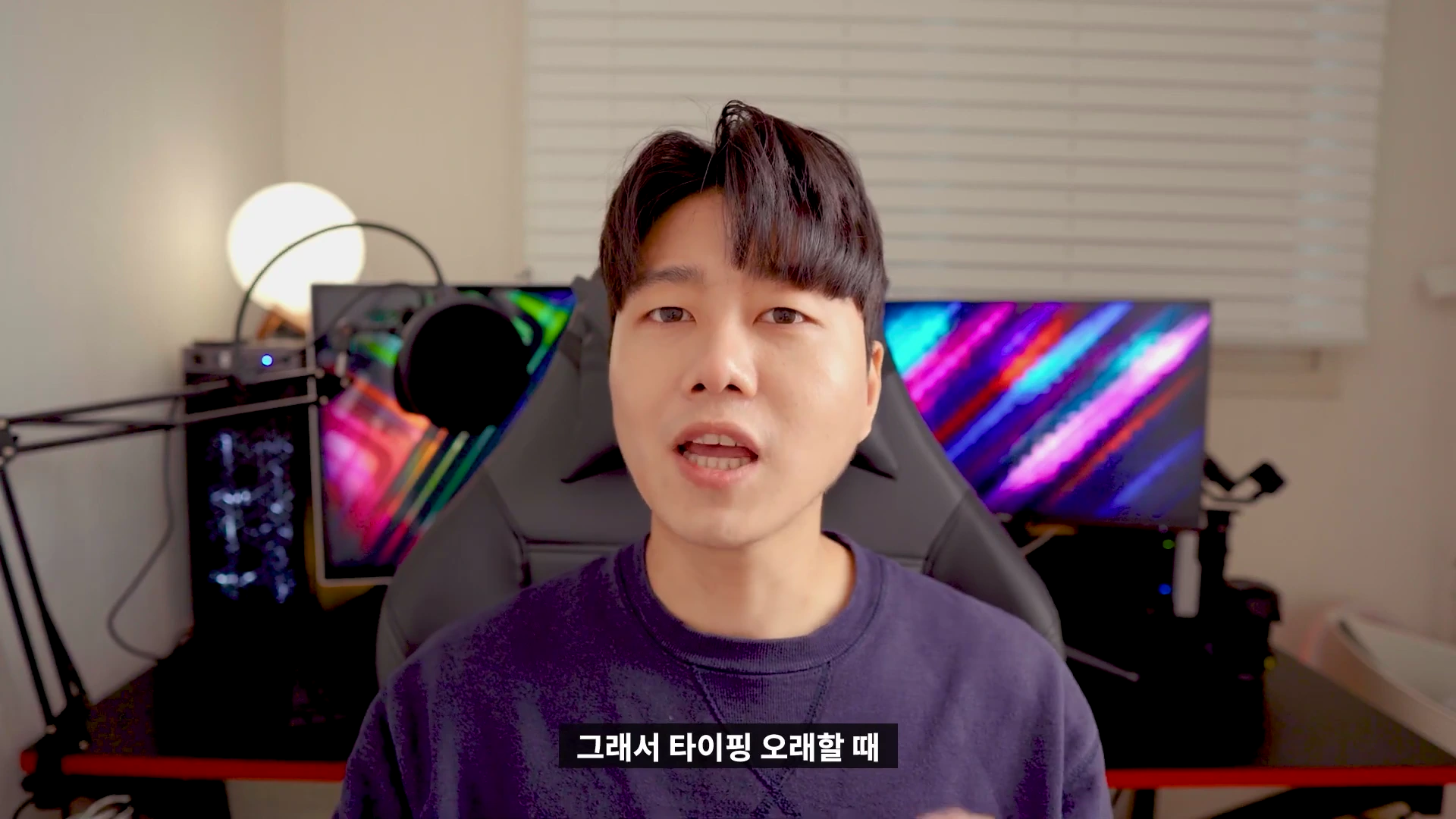 책상 앞에 앉아 카메라를 응시하며 이야기하는 남성