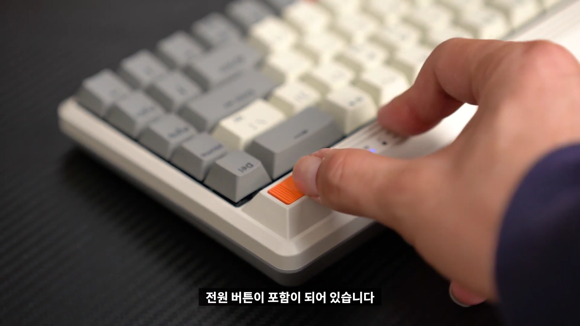 손가락으로 듀가드 퓨전 키보드 우측 상단의 주황색 전원 버튼을 누르는 모습