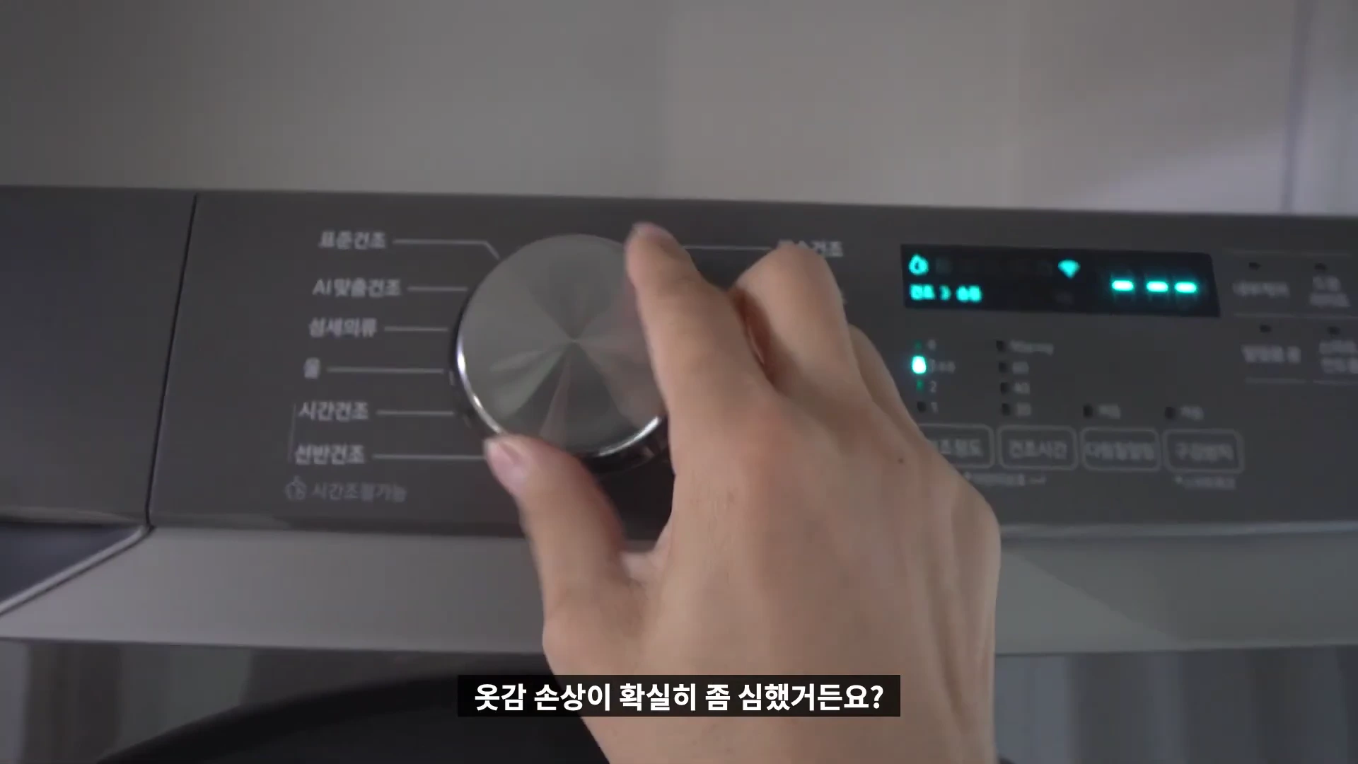 건조기 조작부의 다이얼을 손으로 돌려 코스를 선택하는 모습