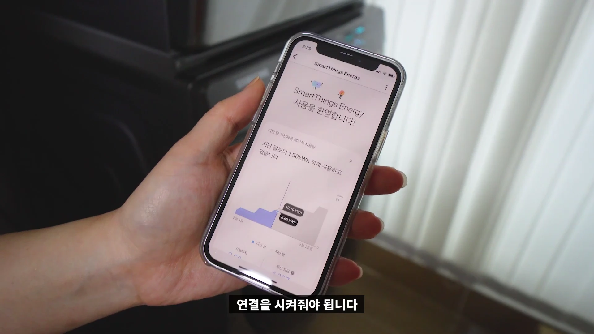 스마트폰 화면에 에너지 사용량을 보여주는 앱이 실행되어 있고, 손으로 기기를 들고 있는 모습