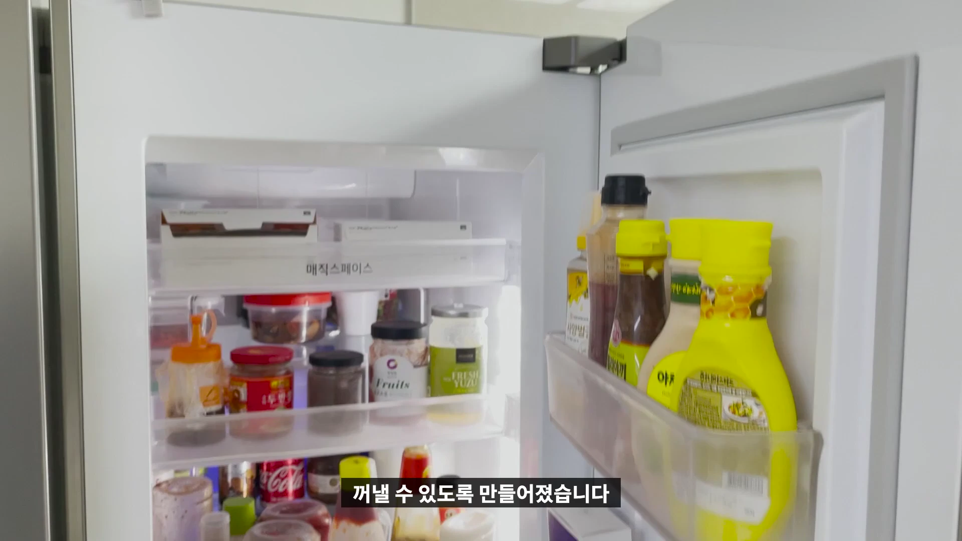 냉장고 문에 달린 매직스페이스 수납공간이 열려 있고 각종 소스와 식재료가 정리되어 있는 모습