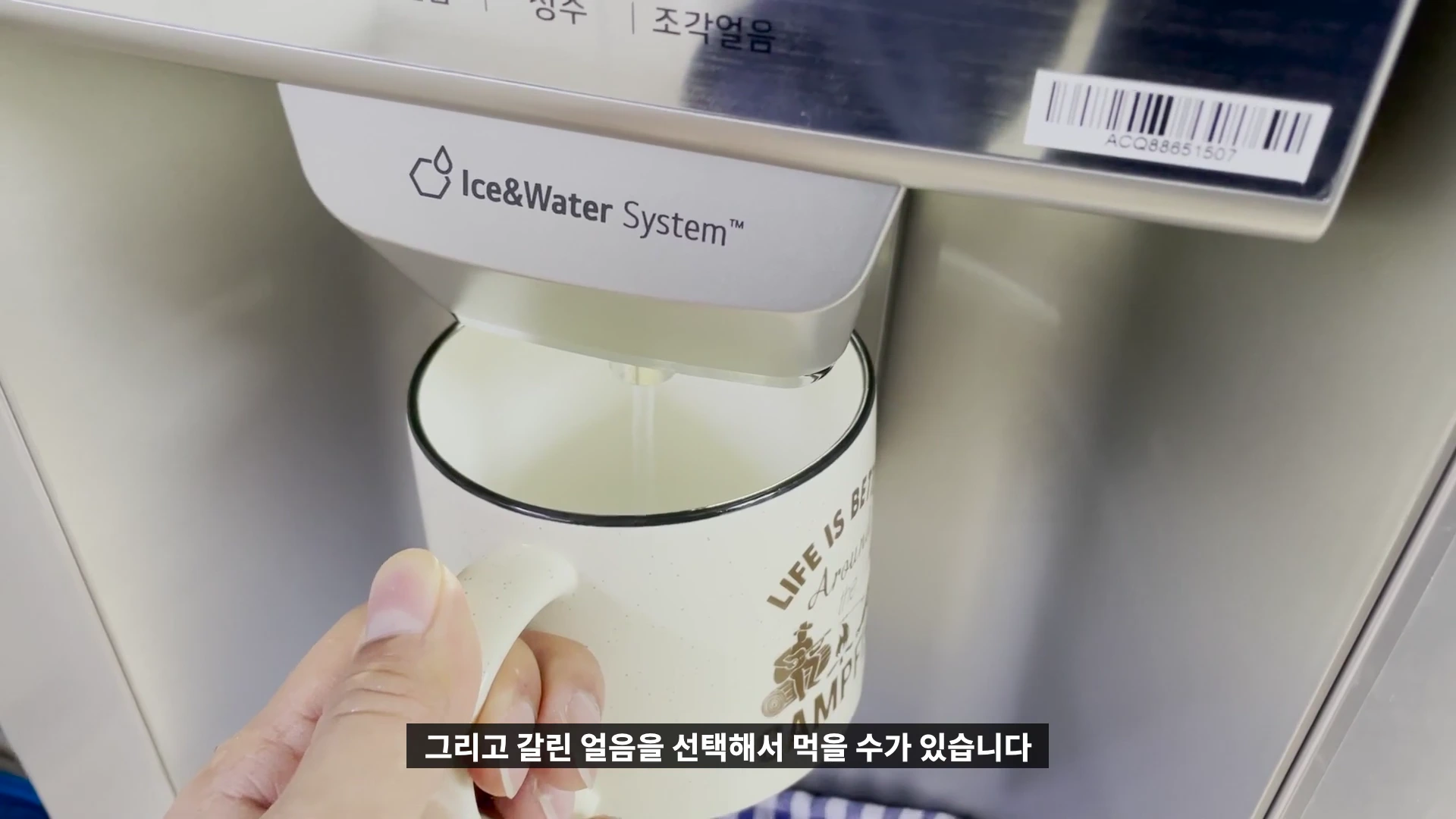 냉장고 외부 디스펜서에서 머그컵으로 물이 나오는 모습