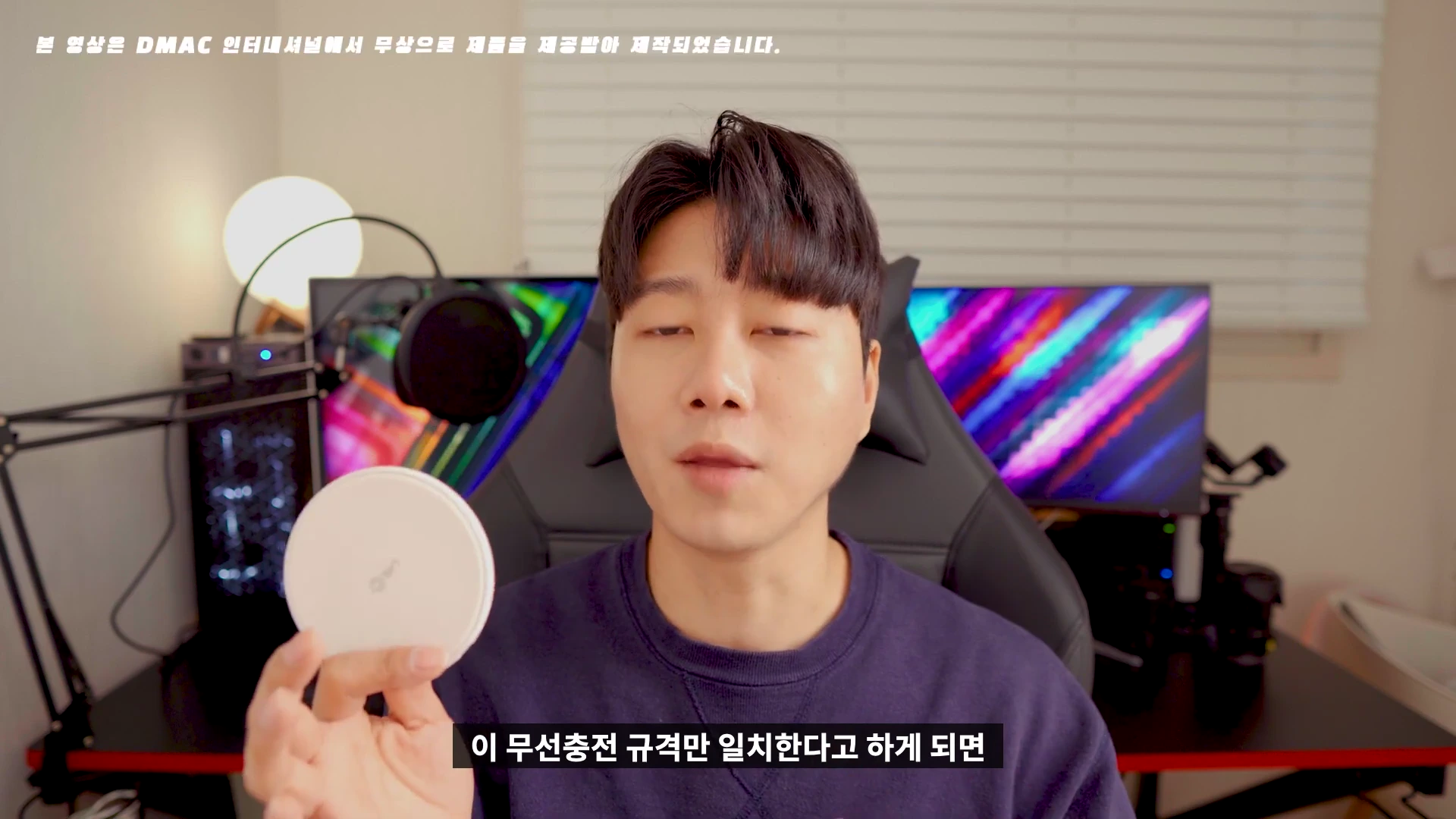 한 남성이 손에 원형의 흰색 무선 충전 패드를 들고 설명하고 있는 모습