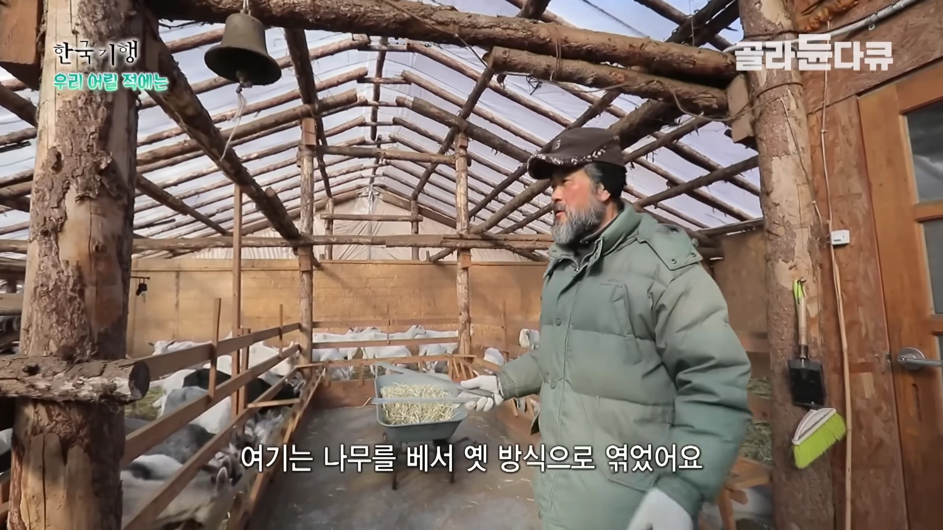 나무로 직접 엮어 만든 축사 안에서 산양들에게 줄 먹이를 살피는 중년 남성의 모습