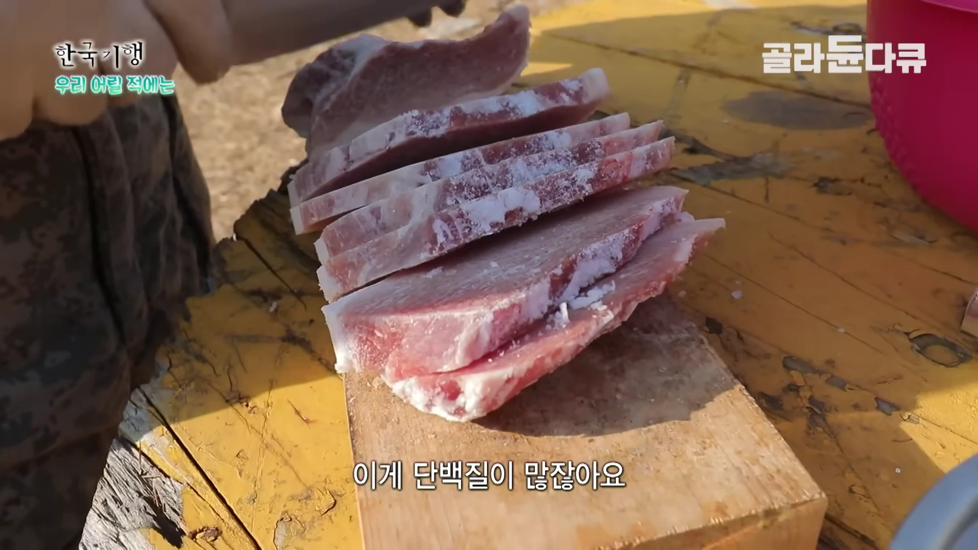 나무 도마 위에서 칼로 살코기를 얇게 썰고 있는 모습