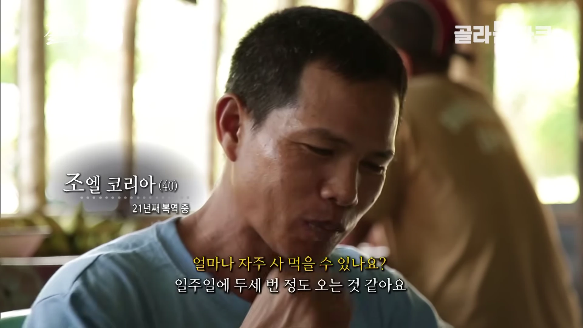 푸른색 티셔츠를 입은 40세 조엘 코리아씨가 인터뷰에 응하고 있는 모습